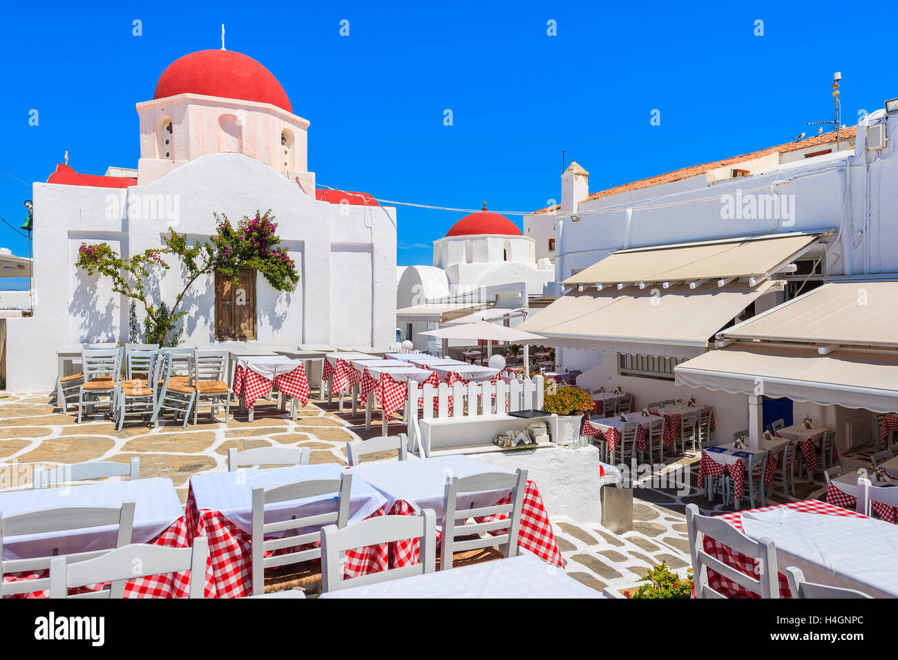 Tables de taverne devant une église dans la ville de Mykonos, Cyclades, Grèce Banque D'Images