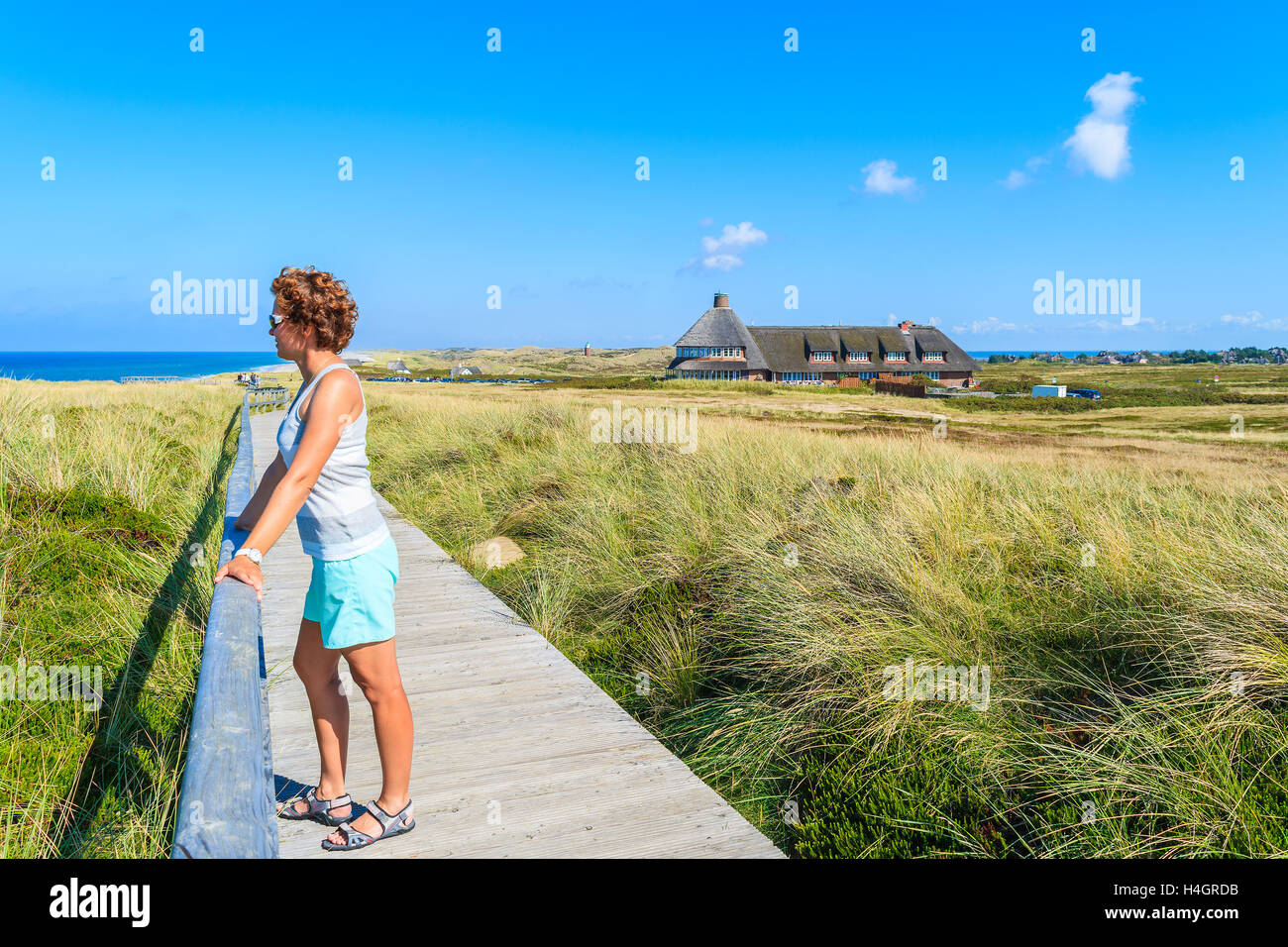 Jeune femme debout sur touristiques sentier pédestre le long d'une côte de l'île de Sylt, Allemagne Banque D'Images
