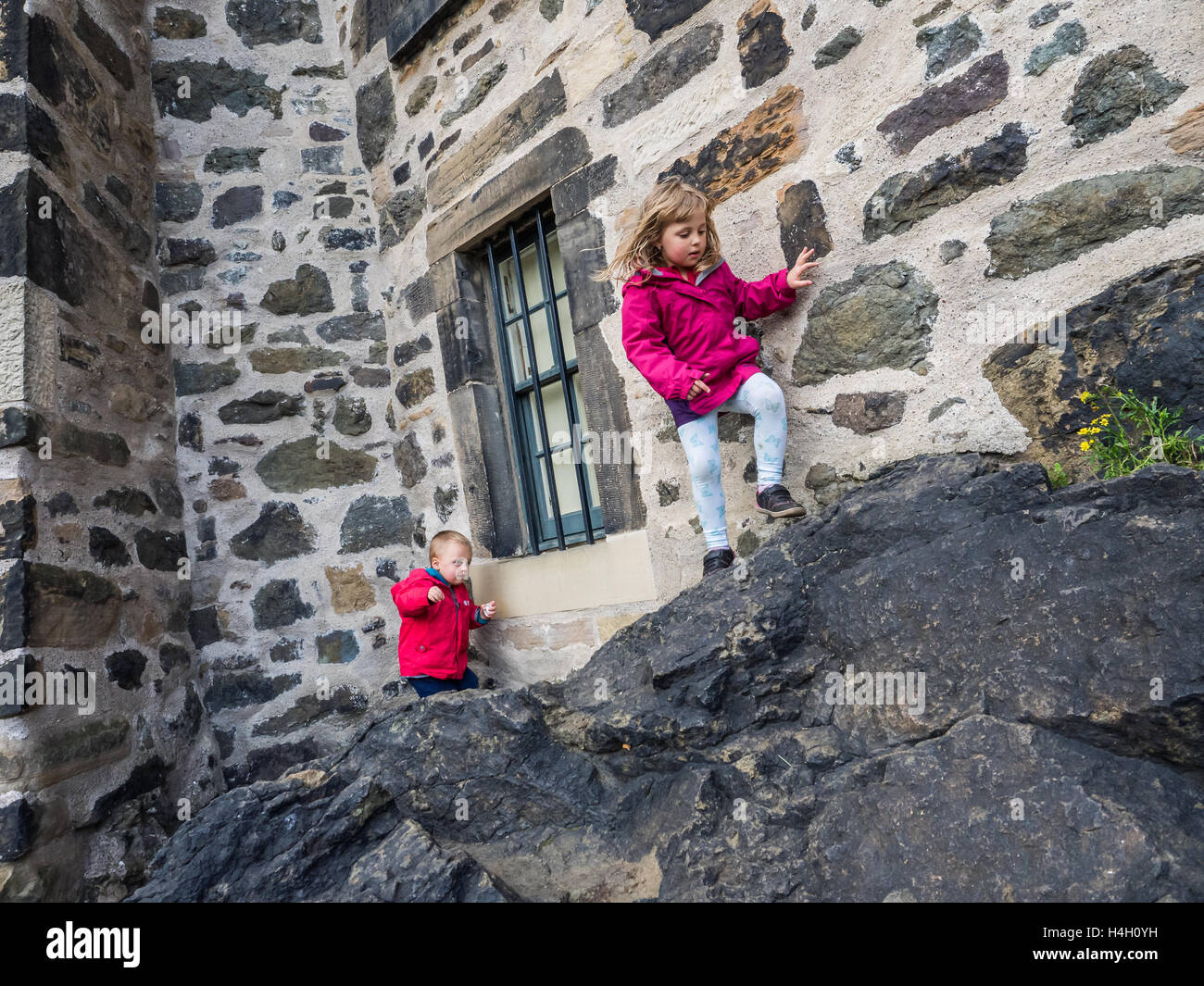 Petit garçon et fille escalade rochers pour atteindre le mur sur le petit château de Calton Hill, à Édimbourg, Écosse Banque D'Images