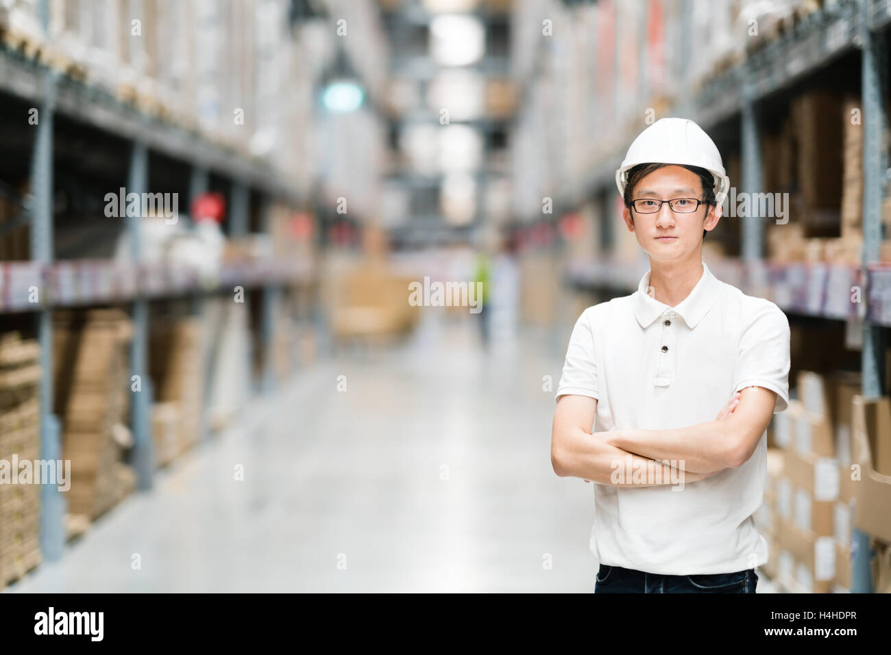 Beau jeune ingénieur ou technicien de l'Asie ou de travailleur, d'entrepôt ou d'arrière-plan flou en usine, l'industrie ou concept logistique, avec Banque D'Images