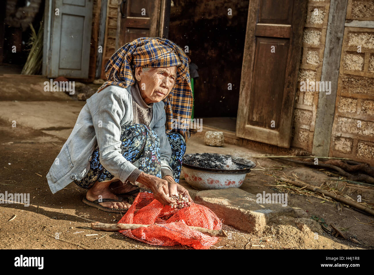 Vieille Femme travaillant en face de sa maison Banque D'Images