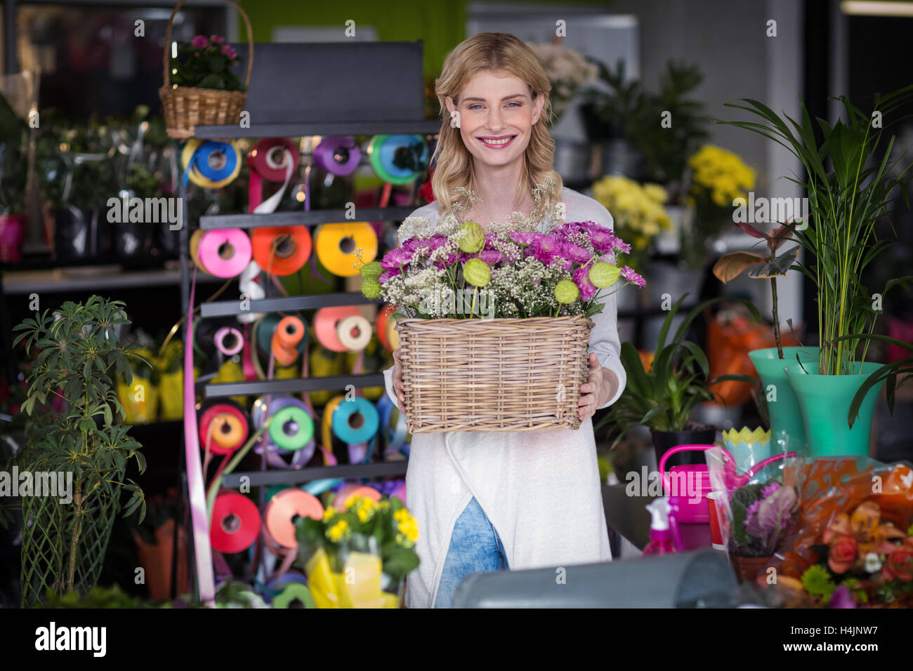 Happy female florist holding panier de fleurs Banque D'Images