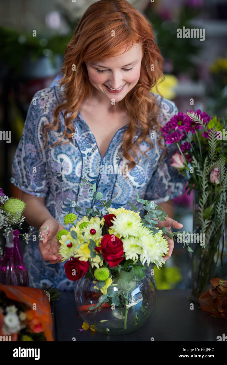 Female florist vérification d'un arrangement de fleurs dans un vase Banque D'Images Female florist vérification d'un arrangement de fleurs dans un vase Banque D'Images