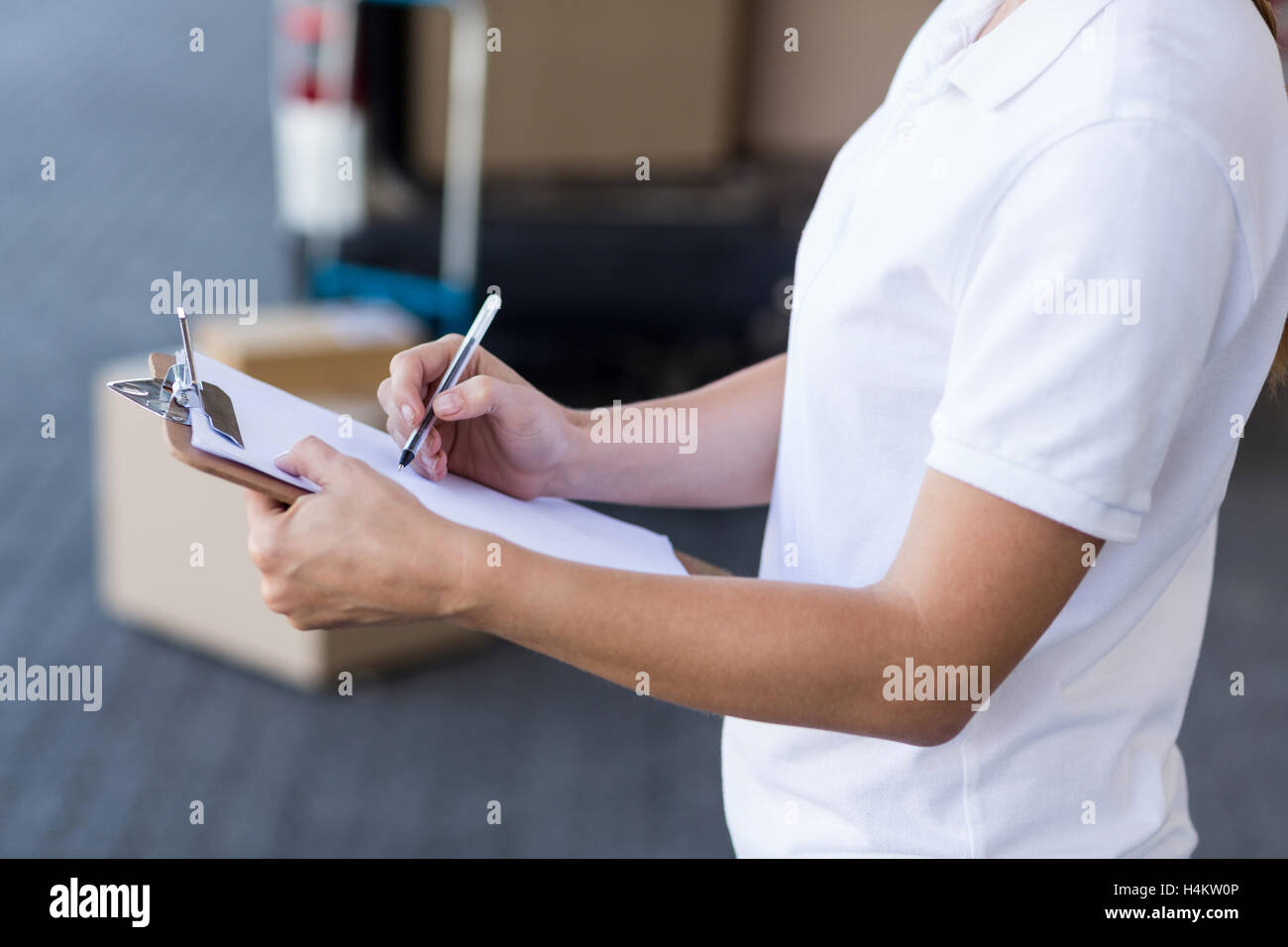 Mid section de livraison woman writing on clipboard Banque D'Images