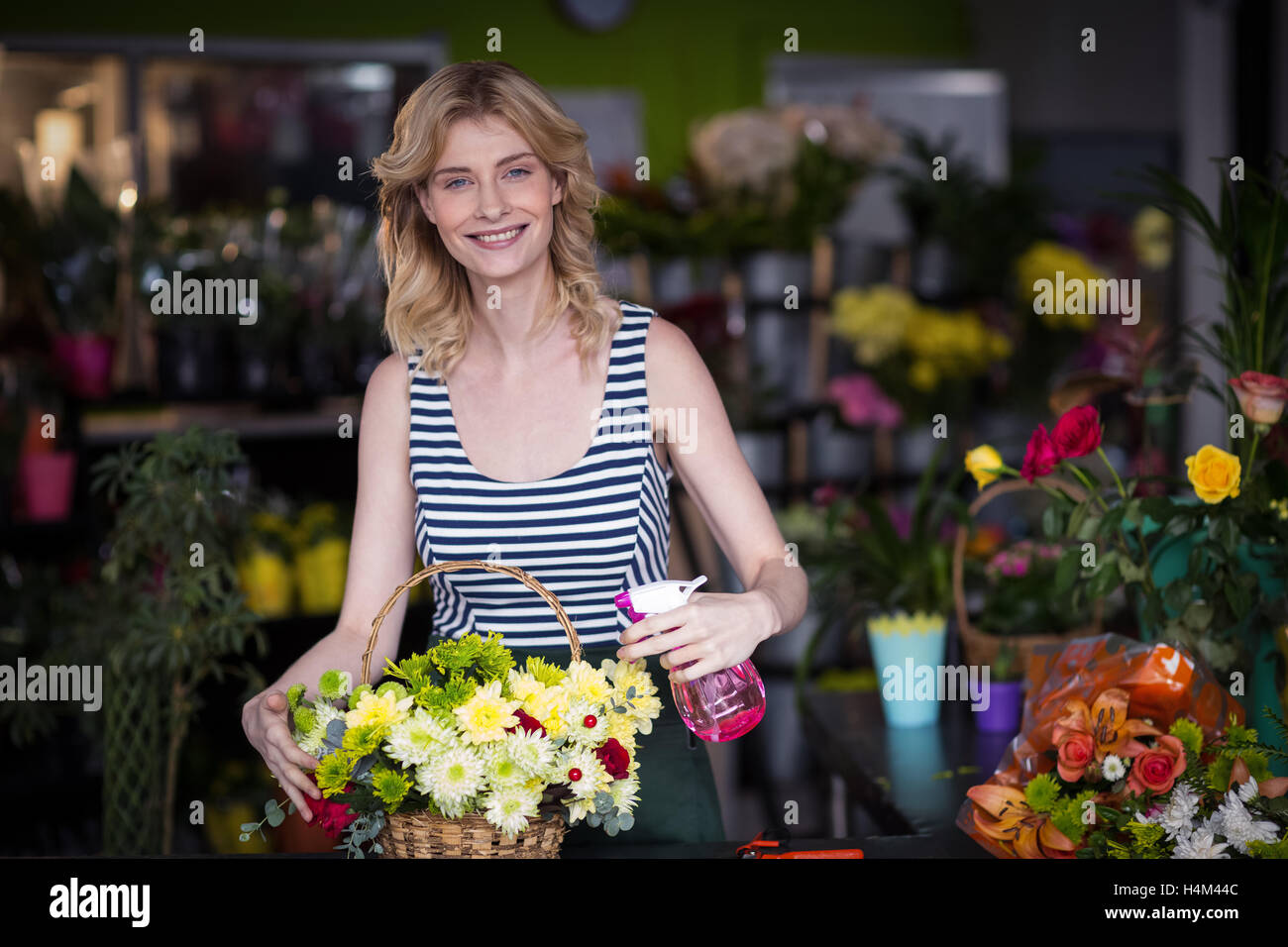 Les fleuristes, pulvériser de l'eau sur les fleurs dans le magasin de fleurs Banque D'Images Les fleuristes, pulvériser de l'eau sur les fleurs dans le magasin de fleurs Banque D'Images