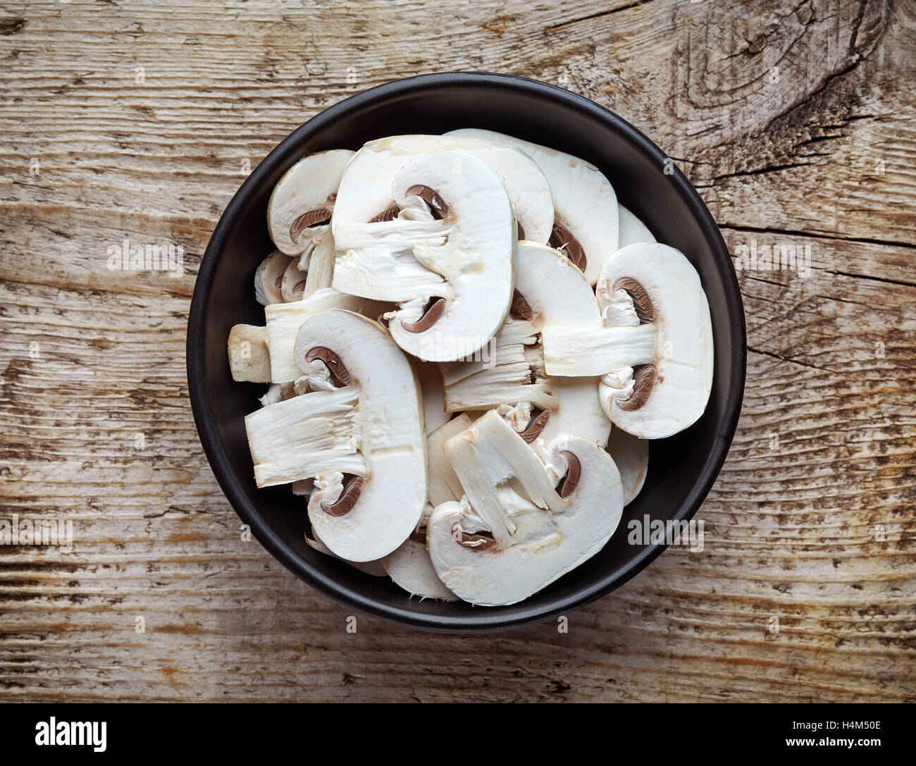 Bol de champignons frais tranchés sur table en bois, vue du dessus Banque D'Images