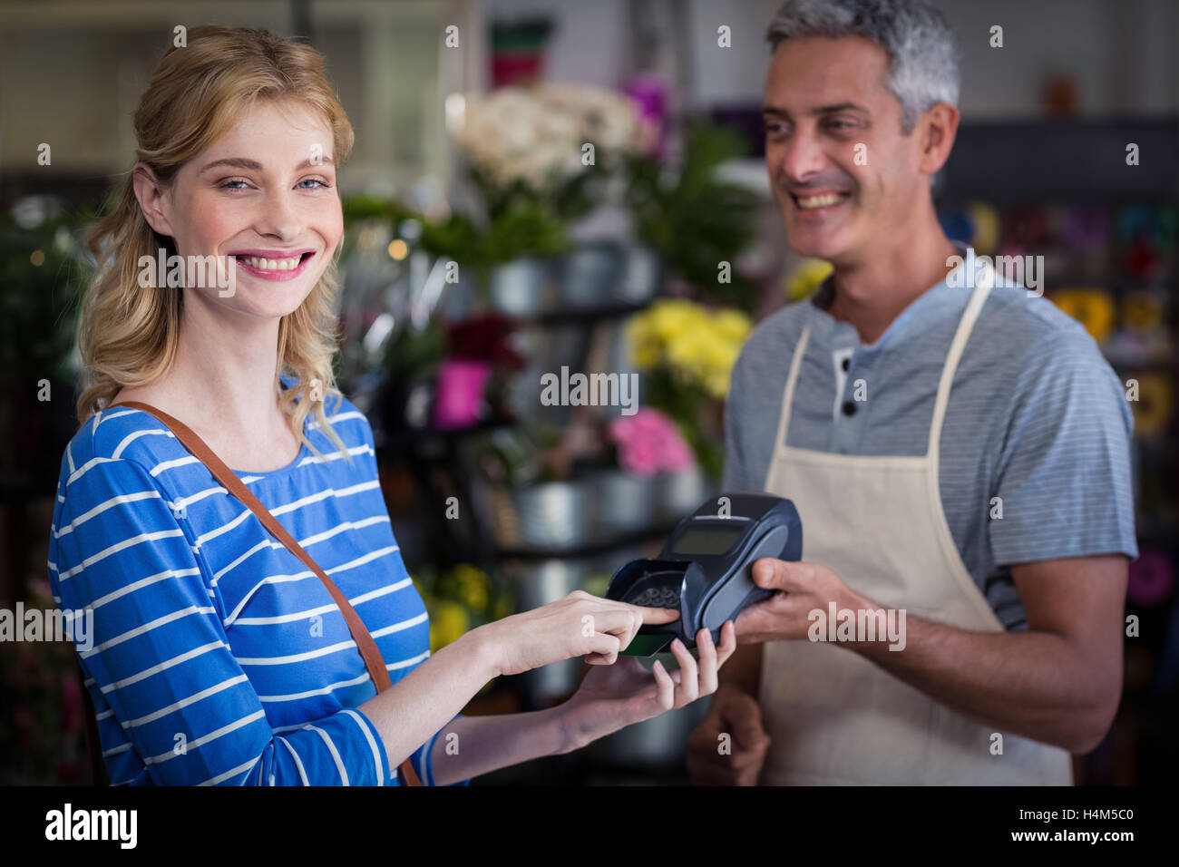 Smiling woman making paiement avec carte de crédit pour un fleuriste Banque D'Images