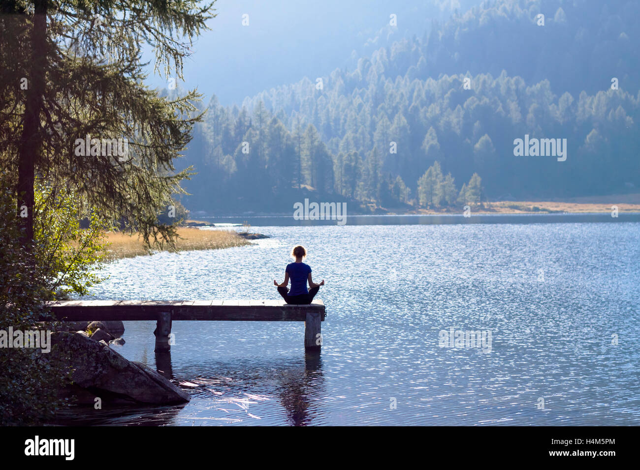 Pretty woman practicing yoga at a lake Banque D'Images