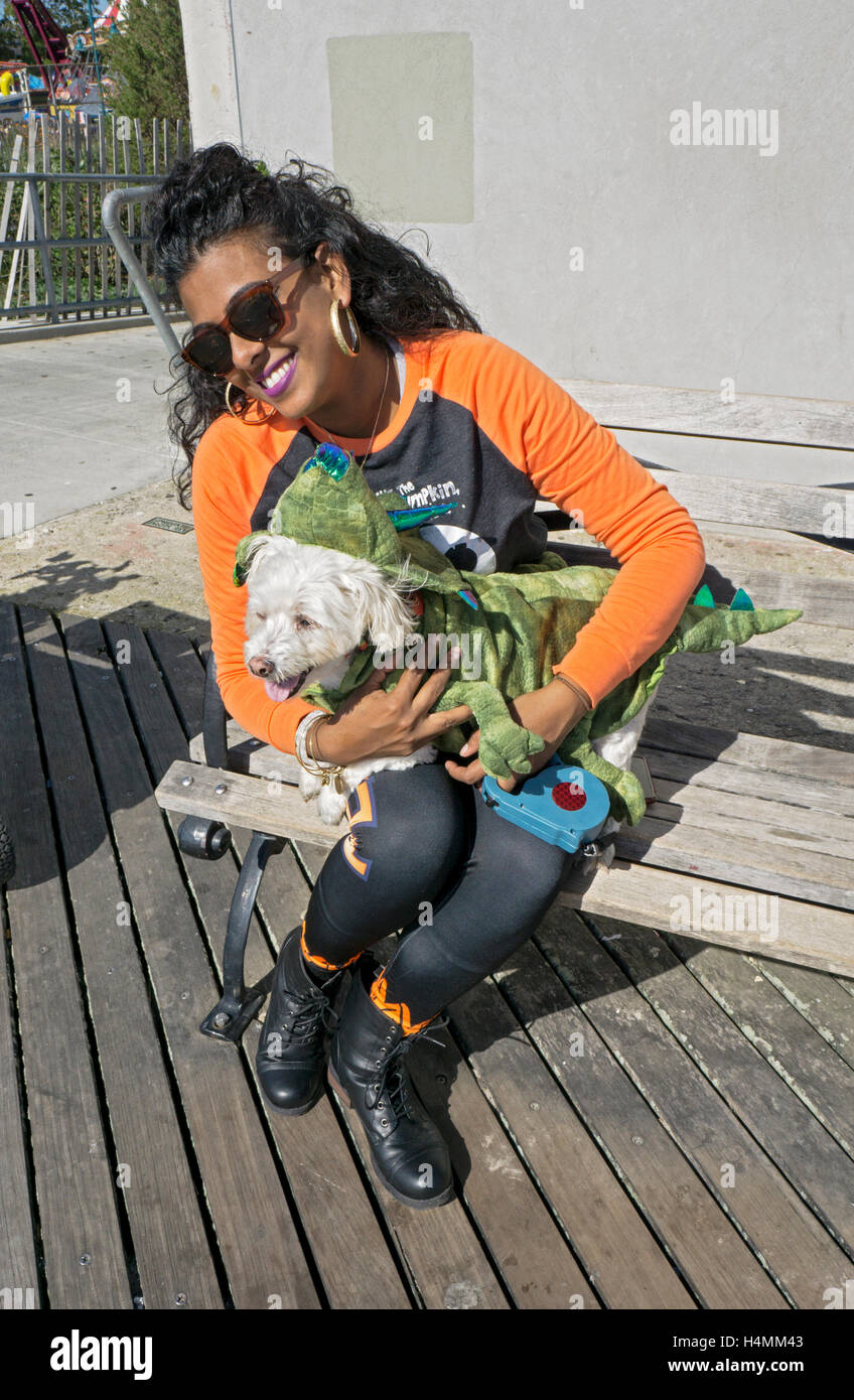 Un chien dans un costume de dragon & propriétaire attrayant dans Coney Island à la récolte d'Halloween Dog Parade et concours de costume. Banque D'Images