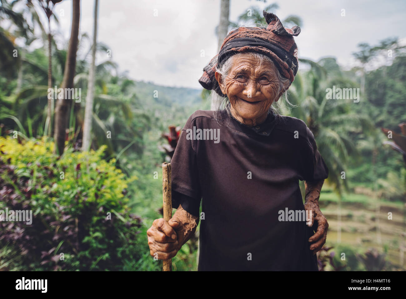 Portrait of senior woman standing avec une canne et souriant. Vieille Femme avec un beau sourire sur son visage à l'extérieur dans la campagne. Banque D'Images