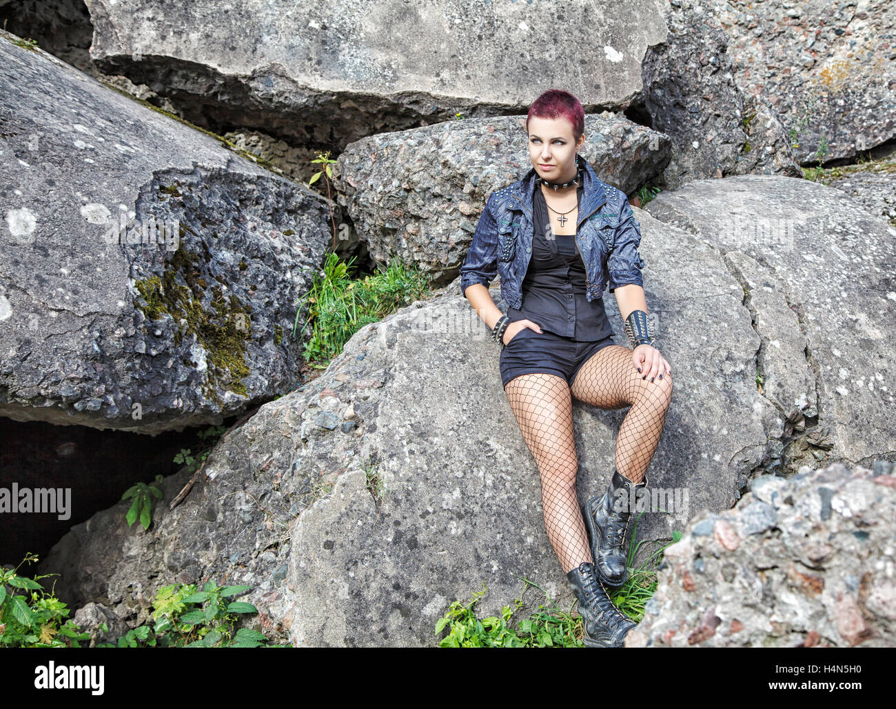 Belle jeune fille punk assis sur une grosse pierre Banque D'Images
