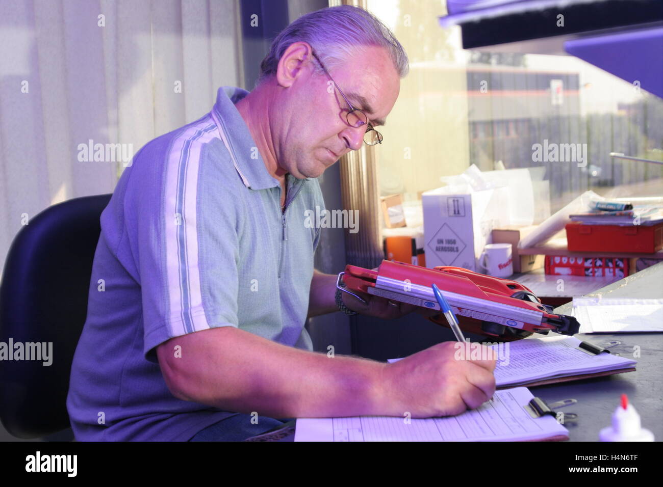 Un ingénieur prend des notes qu'il répare et services des outils électriques à un établi Banque D'Images