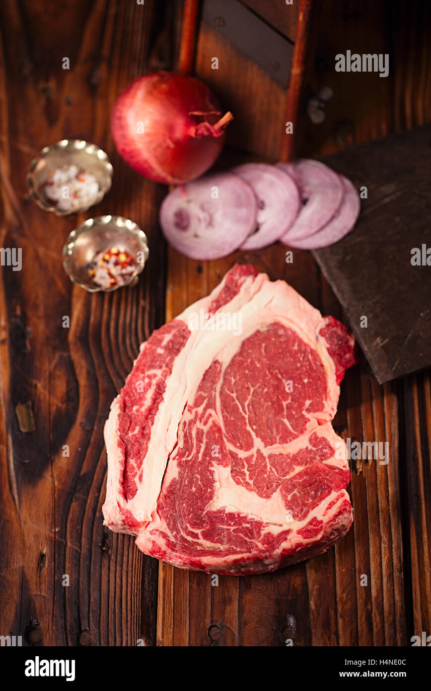 Le boeuf cru Ribeye Steak sur table en bois avec vintage butcher