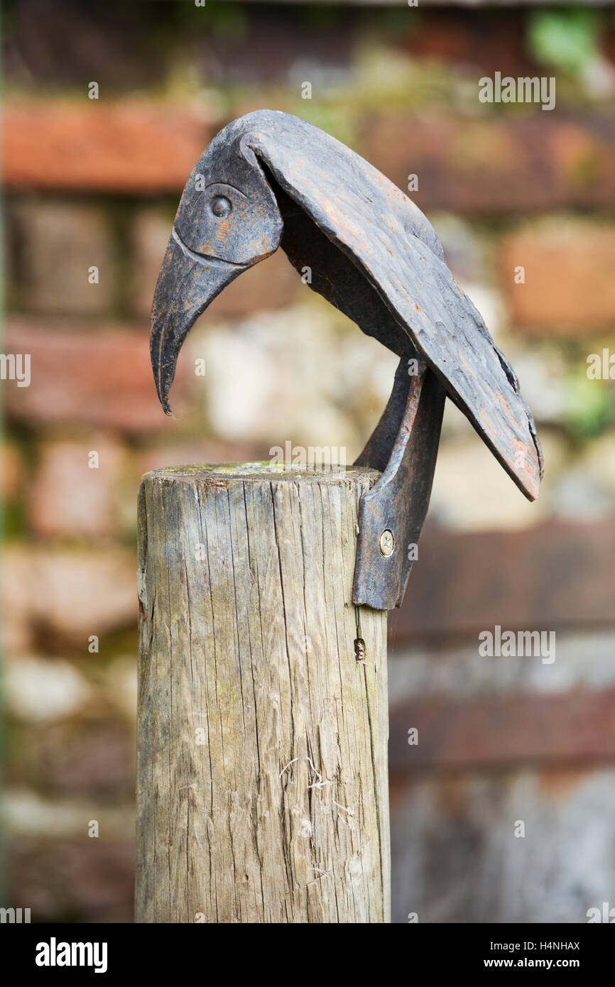 Une sculpture de métal d'un oiseau cloué à un fencepost. Banque D'Images