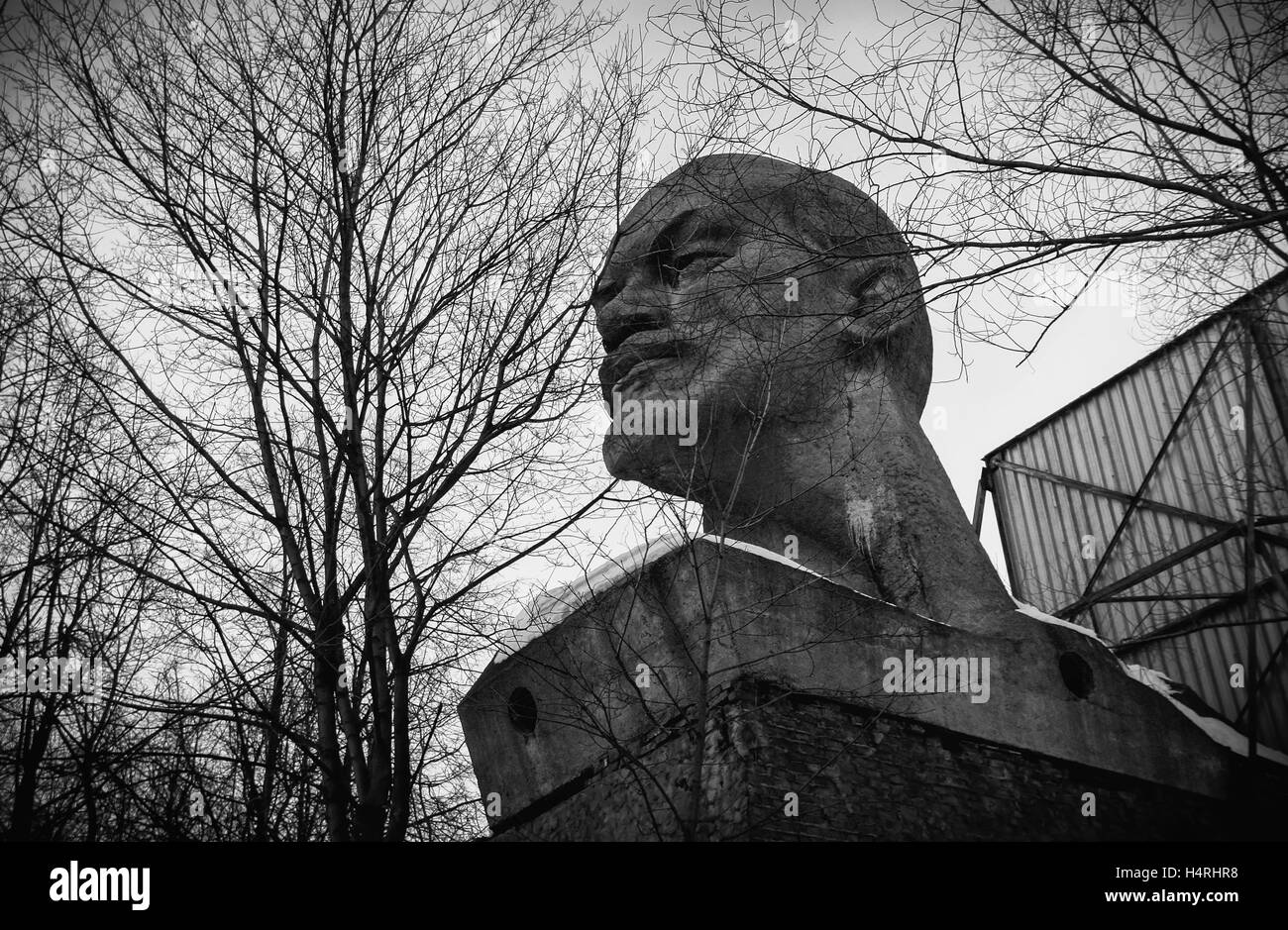 Avec un socle abandonné tête géante de Lénine sur un fond d'arbres morts (noir et blanc) Banque D'Images