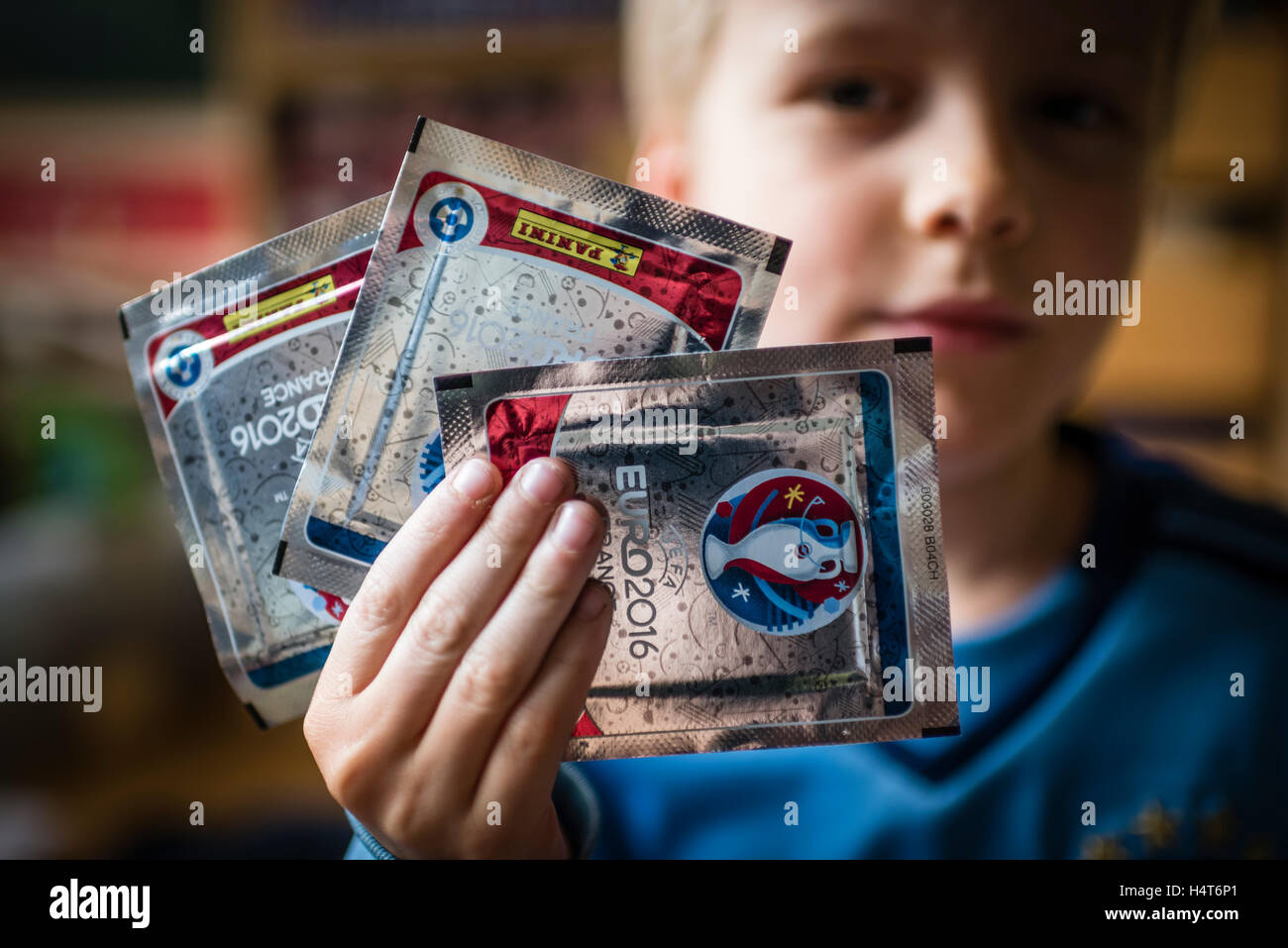 Un garçon de 8 ans est montrant son pack de football Panini trading cards pour l'EURO 2016 Le championnat d'Europe de football de l'UEFA. Banque D'Images