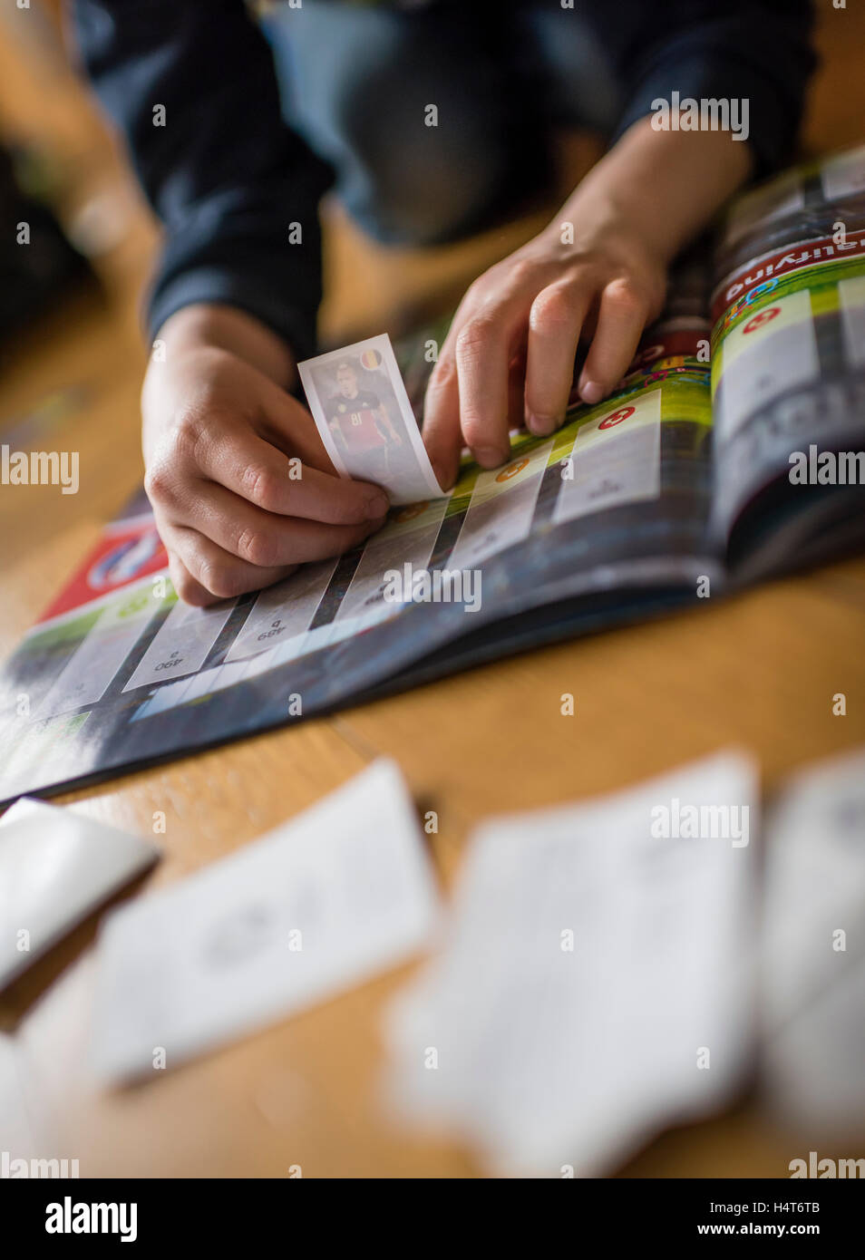 Un garçon de 8 ans est de coller les cartes de football dans sa collection autocollant album. Banque D'Images