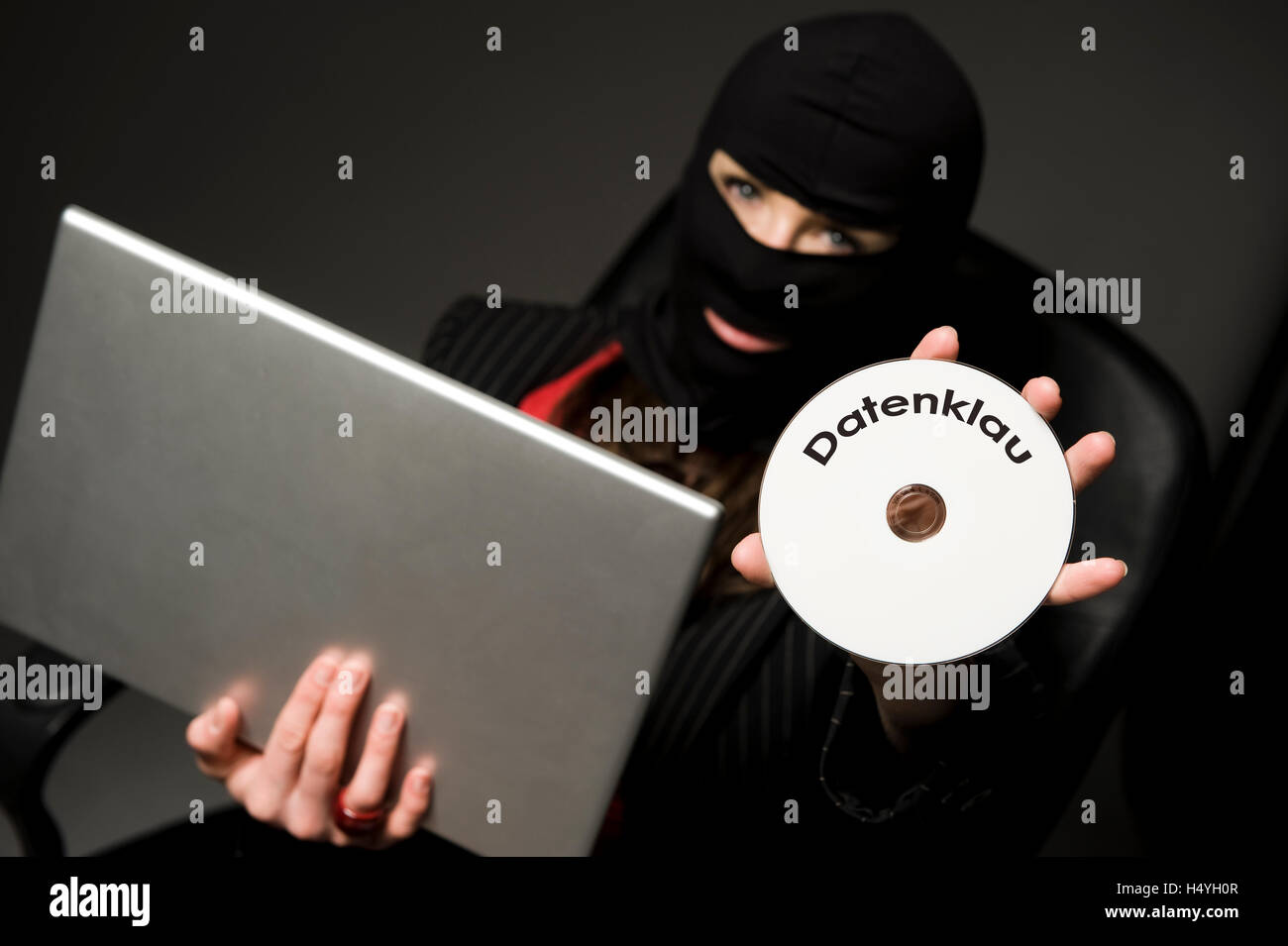 Cambrioleur masqué avec ordinateur portable et un CD avec "atenklau", le piratage de données Banque D'Images