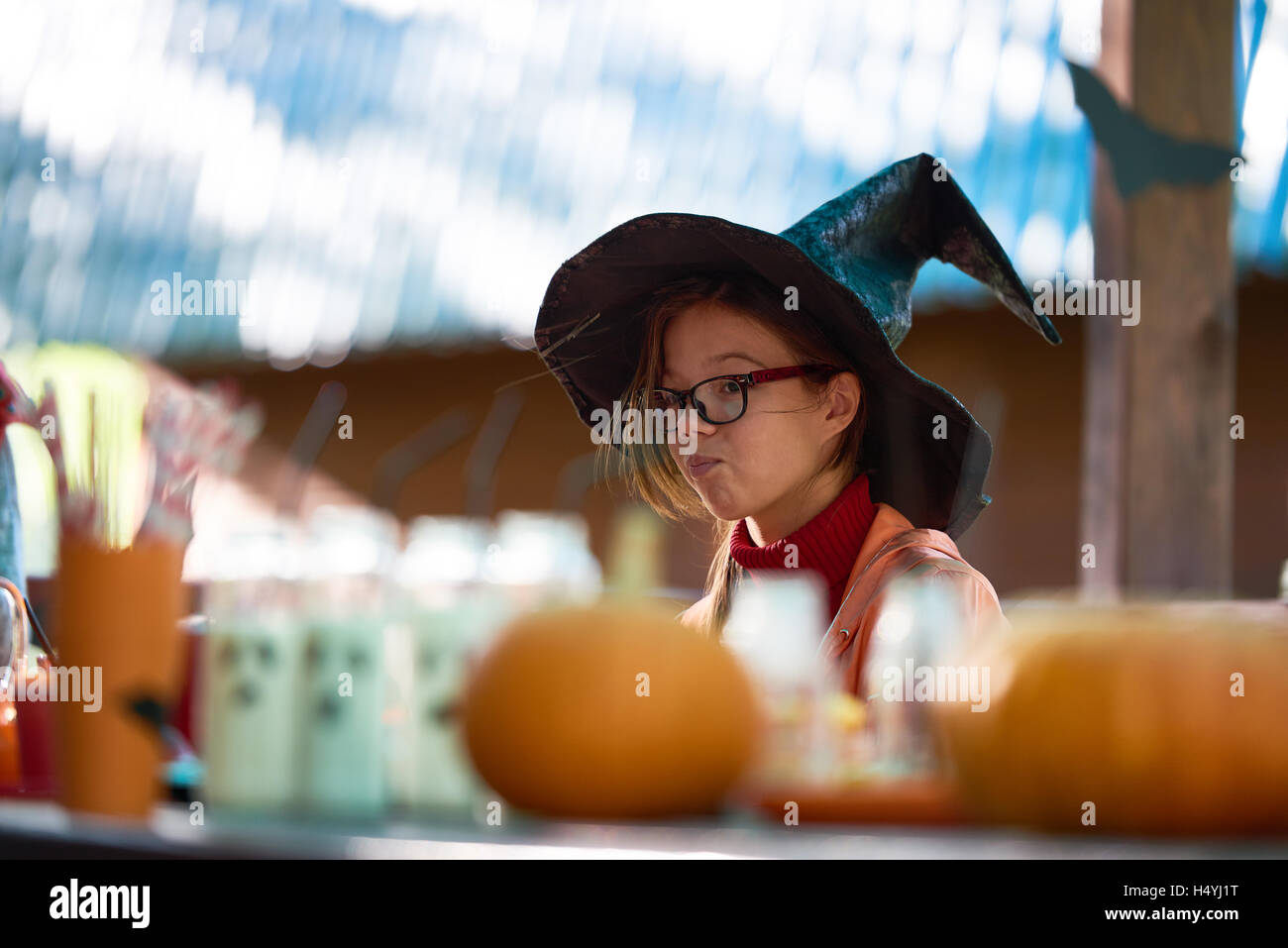Jeune fille en chapeau de sorcière assis par table de fête Banque D'Images