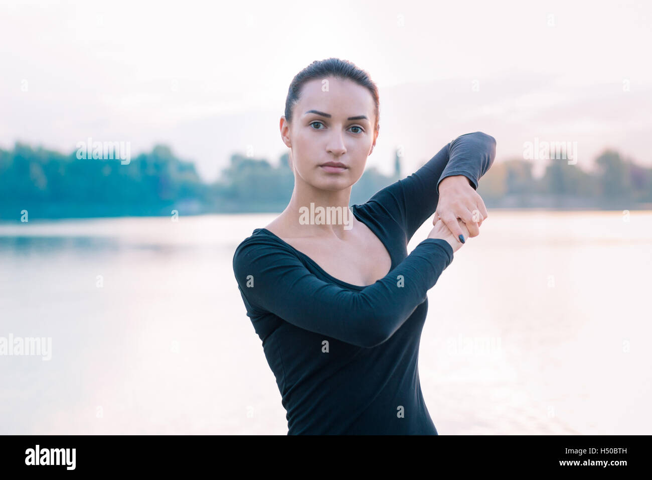 Jeune femme remise en forme s'étend sur la jetée au cours des exercices d'entraînement sur l'heure du lever tôt le matin Banque D'Images