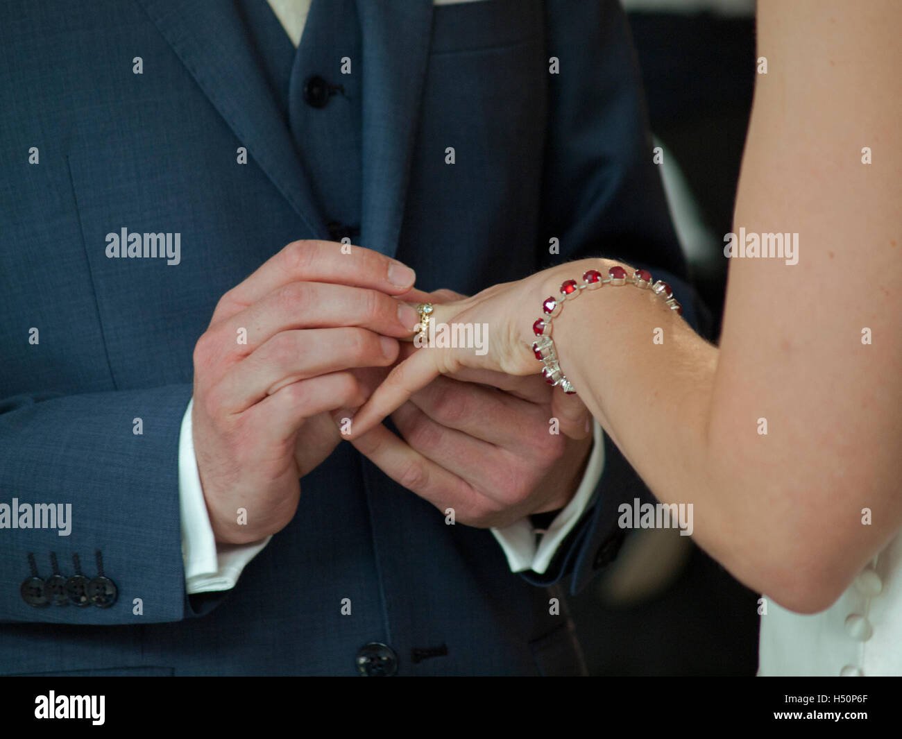 Un groom met un anneau de mariage à son doigt de la mariée Banque D'Images