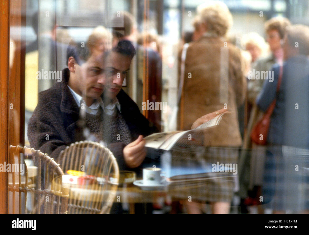 Un homme lisant le journal à un coin salon extérieur parisien Banque D'Images
