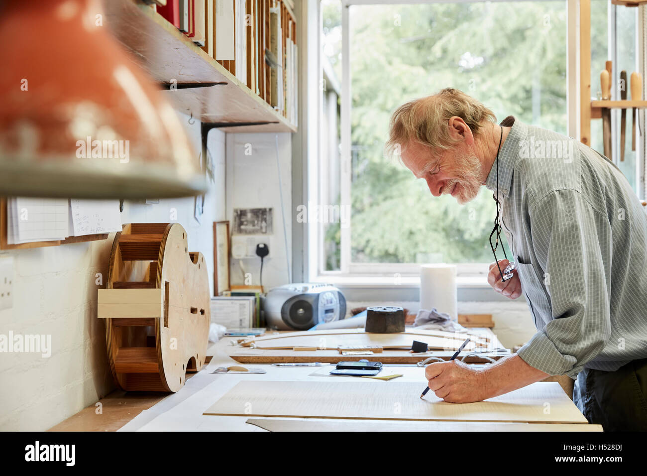 Un luthier à sa planche à dessin faisant ressortir les plans et de l'esquisse d'un nouvel instrument. Banque D'Images