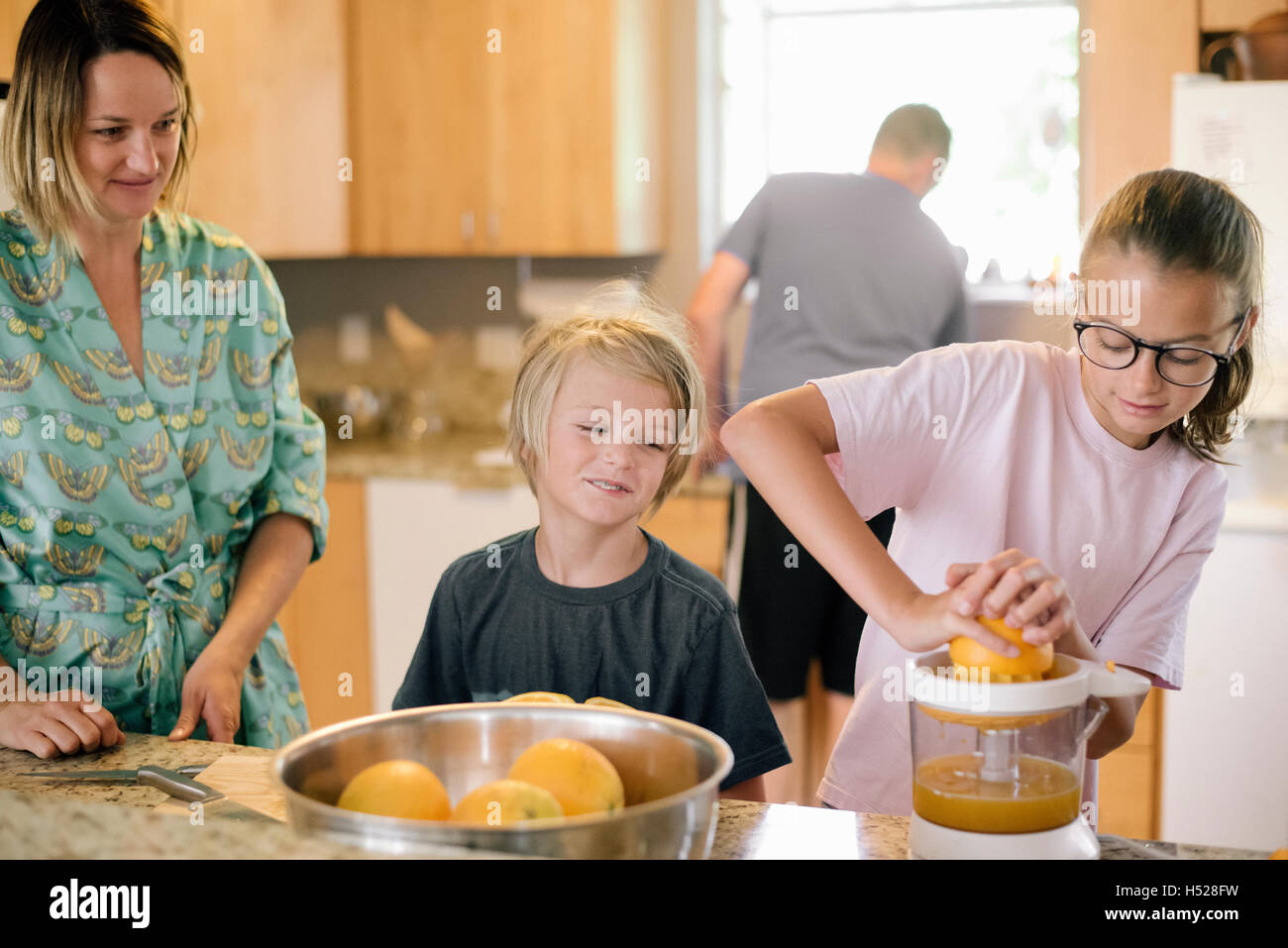 Famille préparer le petit-déjeuner dans une cuisine, girl squeezing oranges. Banque D'Images