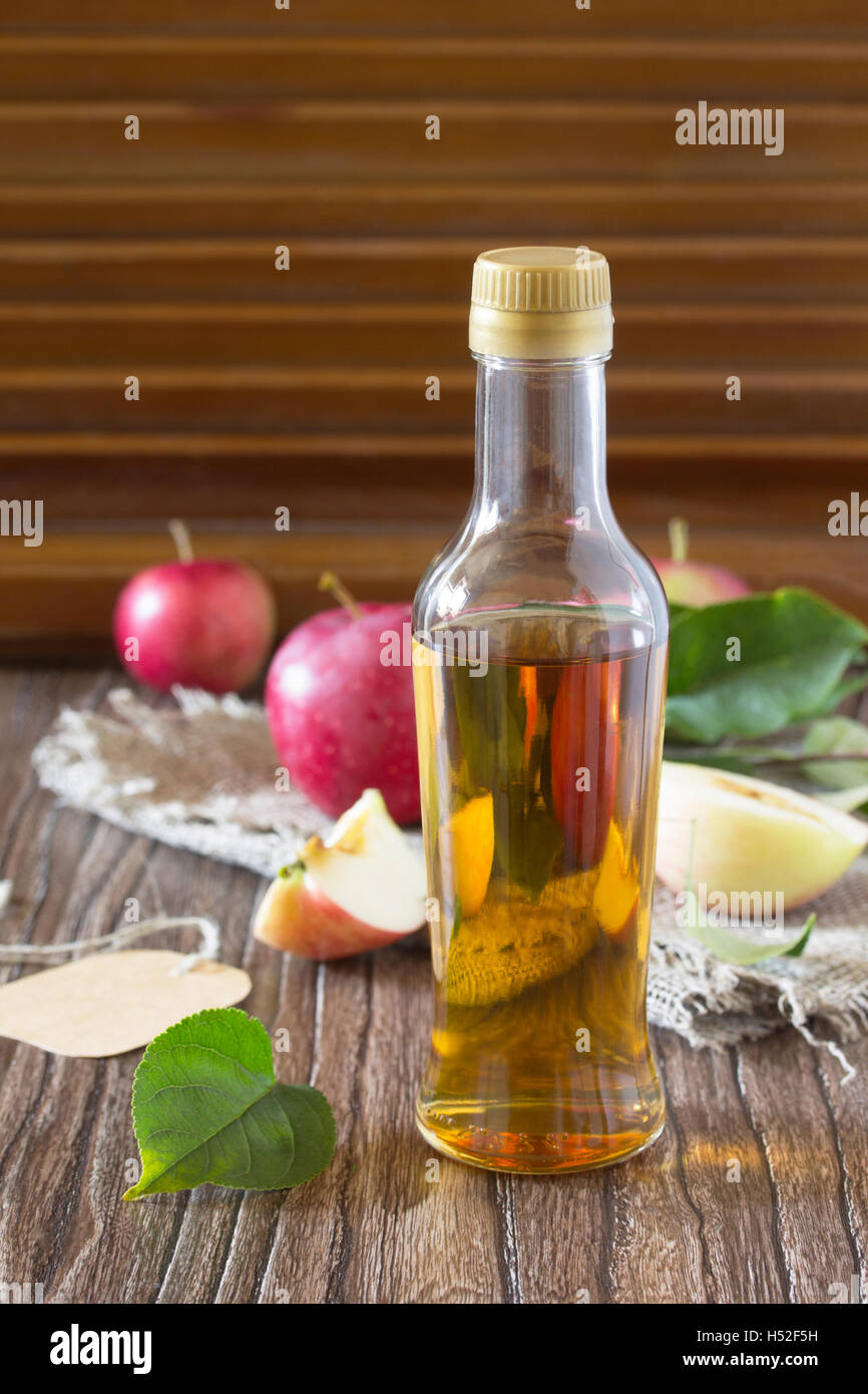 Le vinaigre de cidre de pomme dans une bouteille en verre avec des pommes sur une table en bois. Copie de l'espace pour votre texte. Banque D'Images