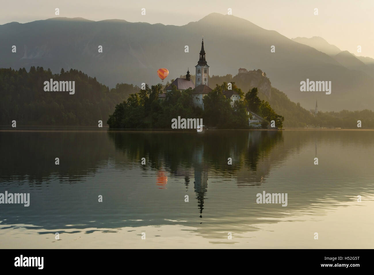 Le lac de Bled avec île, château et montgolfière au lever du soleil en Slovénie Banque D'Images