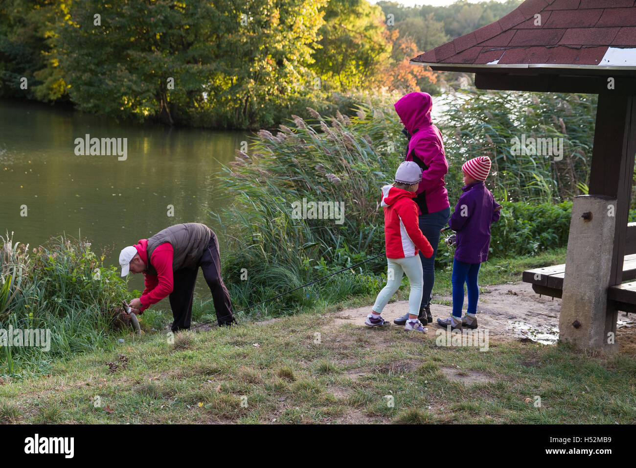 Famille de quatre personnes sur le lac la pêche. Pris le brochet. . Papa poisson, les petites filles sont heureux. De l'automne. Banque D'Images