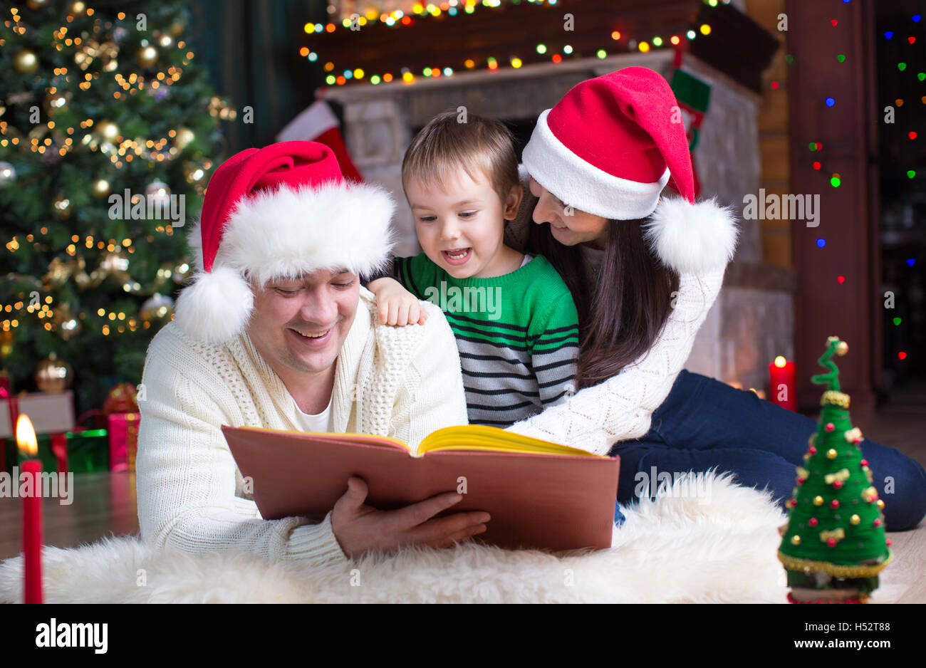 Une famille heureuse de trois lire ensemble sur soirée de Noël Banque D'Images