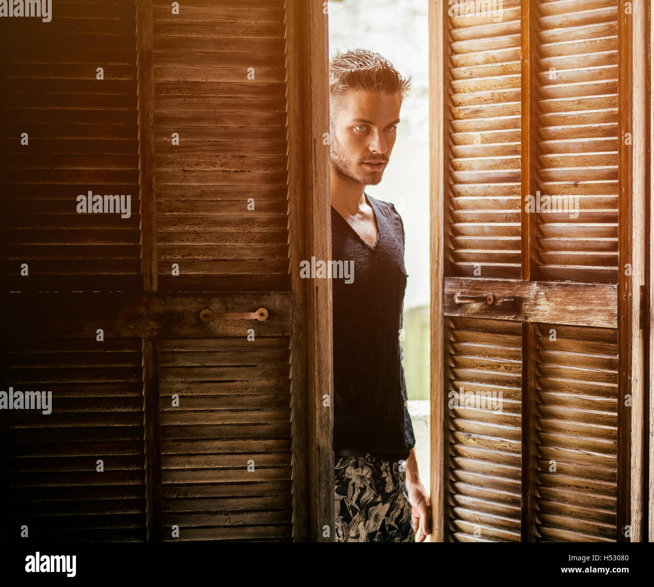 Portrait de beau jeune homme avec barbe en entrant dans la chambre avec les portes en bois Banque D'Images