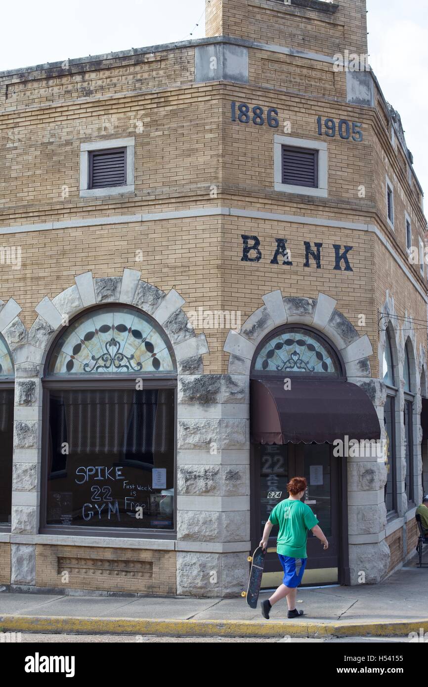 Un adolescent avec un skateboard en face de la Citizen's Bank Building à Van Buren, Arkansas, USA. Banque D'Images