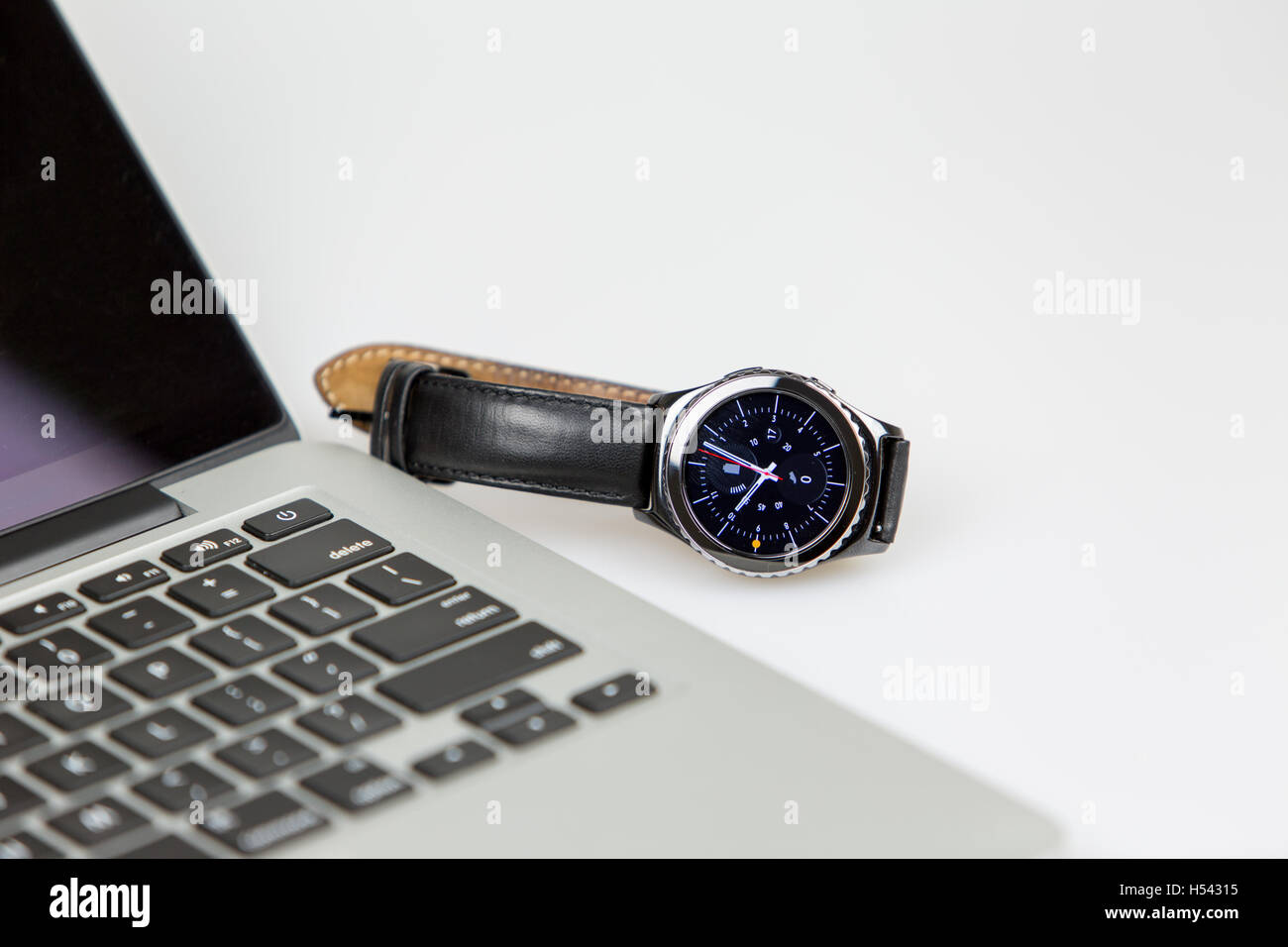Lapto pwith smart watch couché sur le côté gauche de l'ordinateur portable. Réveil sur l'écran et la batterie entièrement chargée. 4 heures sur le wa Banque D'Images