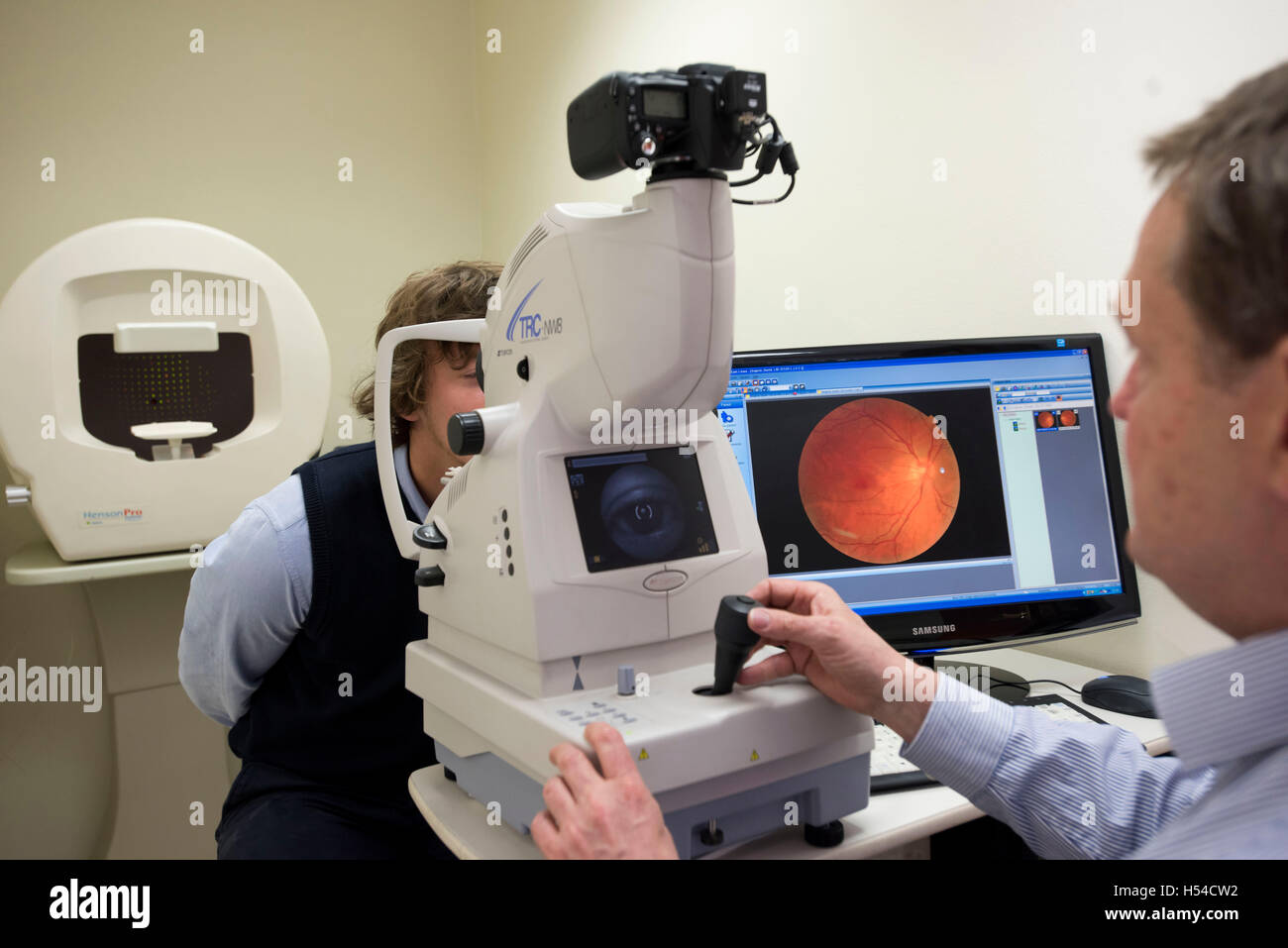 Un opticien d'effectuer un examen de la vue à l'aide d'une tomographie par cohérence optique (OCT) machine. Banque D'Images