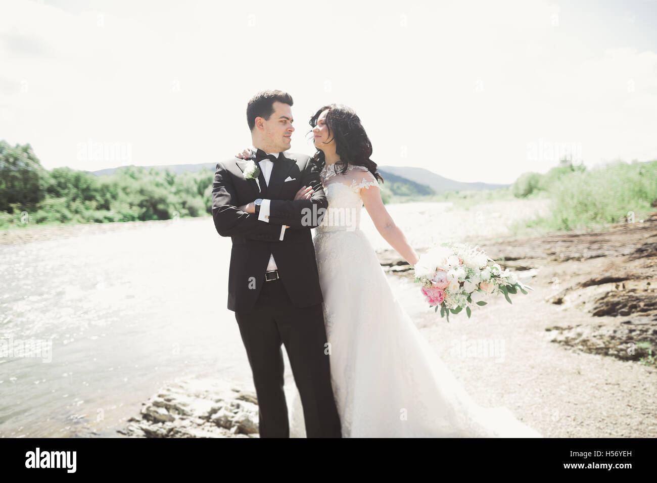 Doux et élégant élégant marié mariée près de rivière avec des pierres. Wedding couple in love Banque D'Images