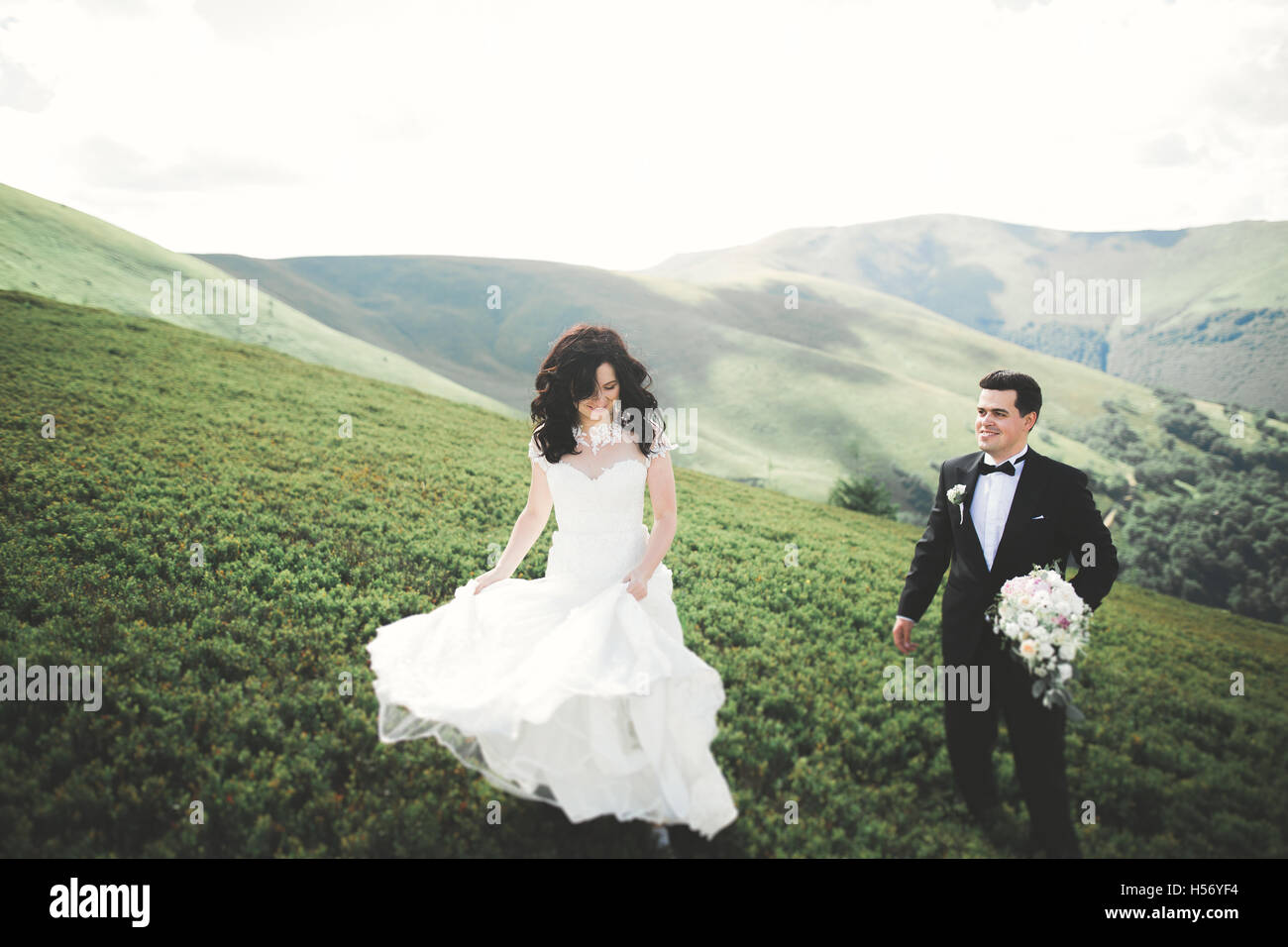Belle et élégante mariée heureuse fabuleux groom posing sur l'arrière-plan de la magnifique montagne ensoleillée Banque D'Images