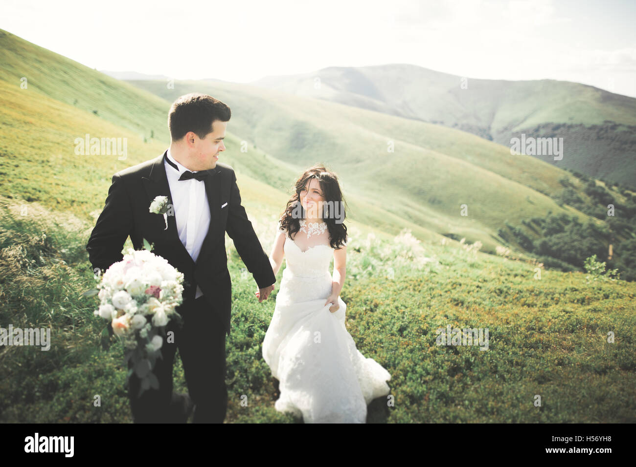 Magnifique mariée et le marié élégant à marche, paysage ensoleillé, couple de mariage cérémonie de luxe avec vue imprenable sur les montagnes, l'espace pour le texte Banque D'Images Magnifique mariée et le marié élégant à marche, paysage ensoleillé, couple de mariage cérémonie de luxe avec vue imprenable sur les montagnes, l'espace pour le texte Banque D'Images