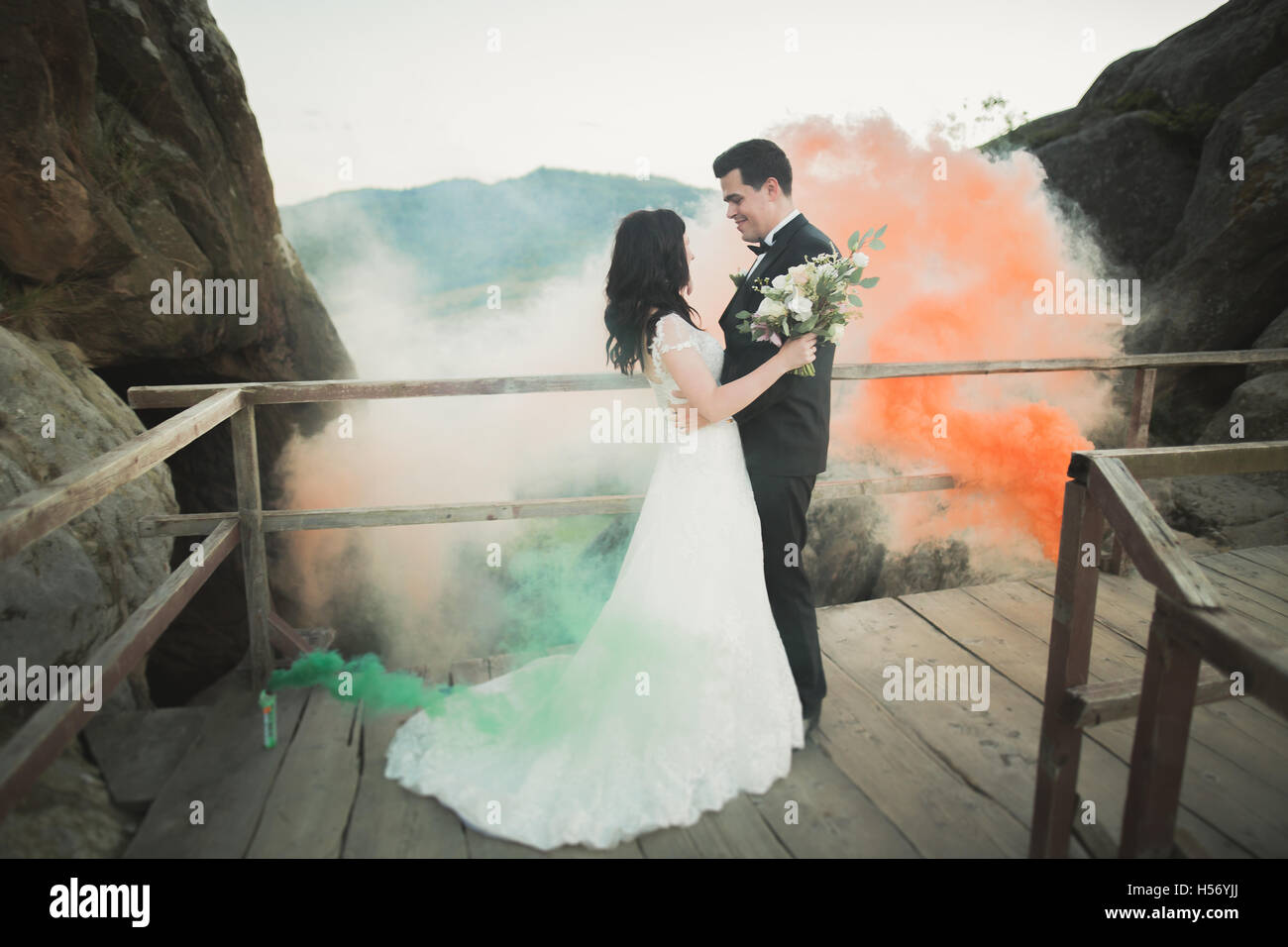 Couple de mariage à proximité de rochers avec la fumée de couleur derrière eux Banque D'Images