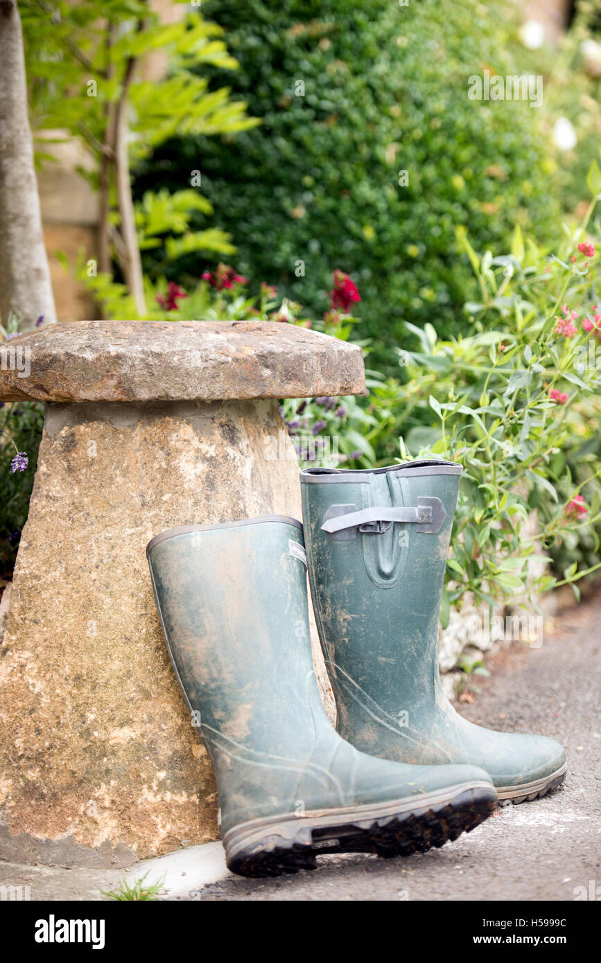 Une paire de bottes wellington appuyé contre une pierre staddle hors d'un pays de Cotswold cottage, UK Banque D'Images
