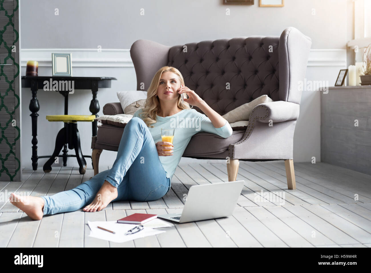 Blonde woman sitting on floor et de parler par téléphone Banque D'Images