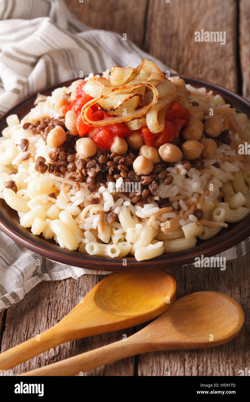 La nourriture végétarienne : kushari de riz, pâtes, pois chiches et lentilles close up sur une plaque verticale. Banque D'Images