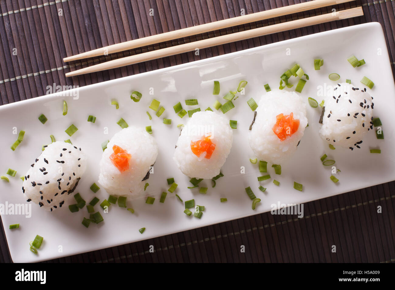 Boules de riz onigiri japonais bourré avec du saumon et sésame sur une assiette blanche horizontale vue du dessus. Banque D'Images