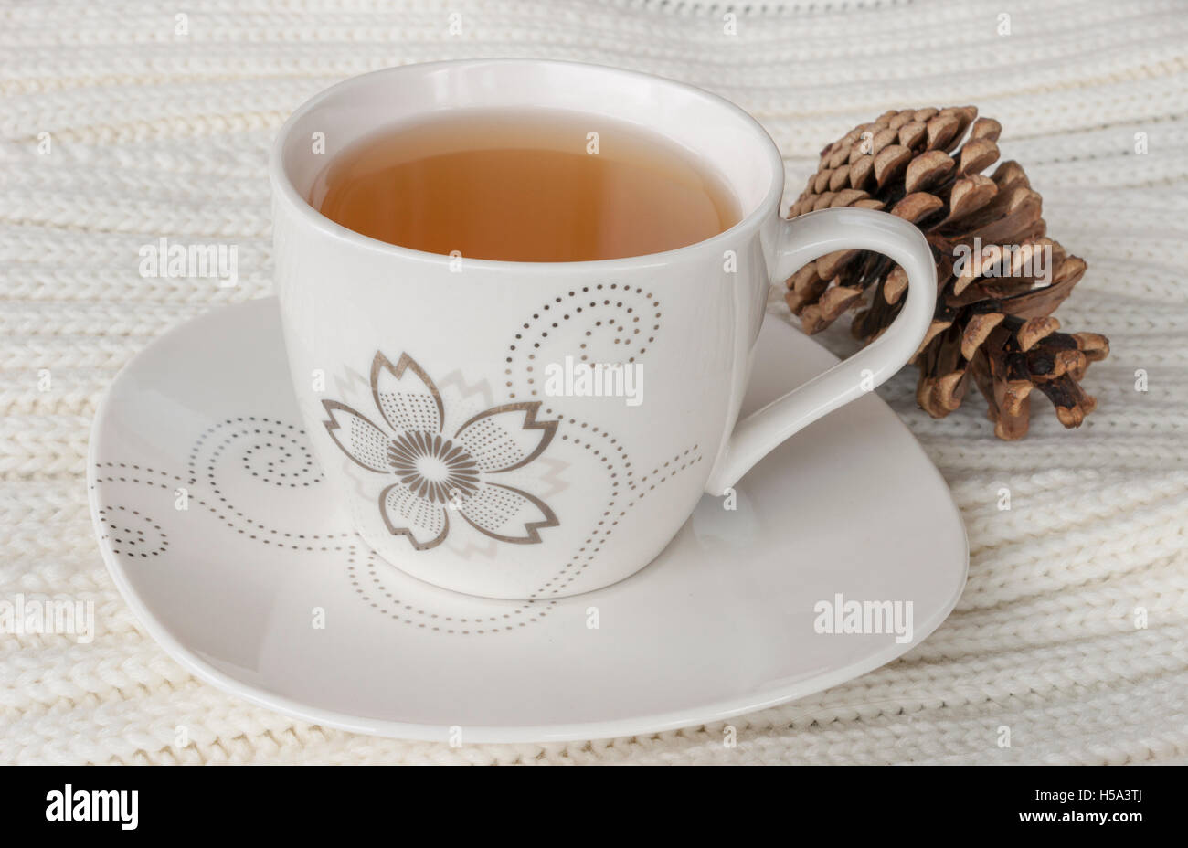 Plateau en Chine tasse et soucoupe, blanc table tricot jeter et pomme de pin. Banque D'Images