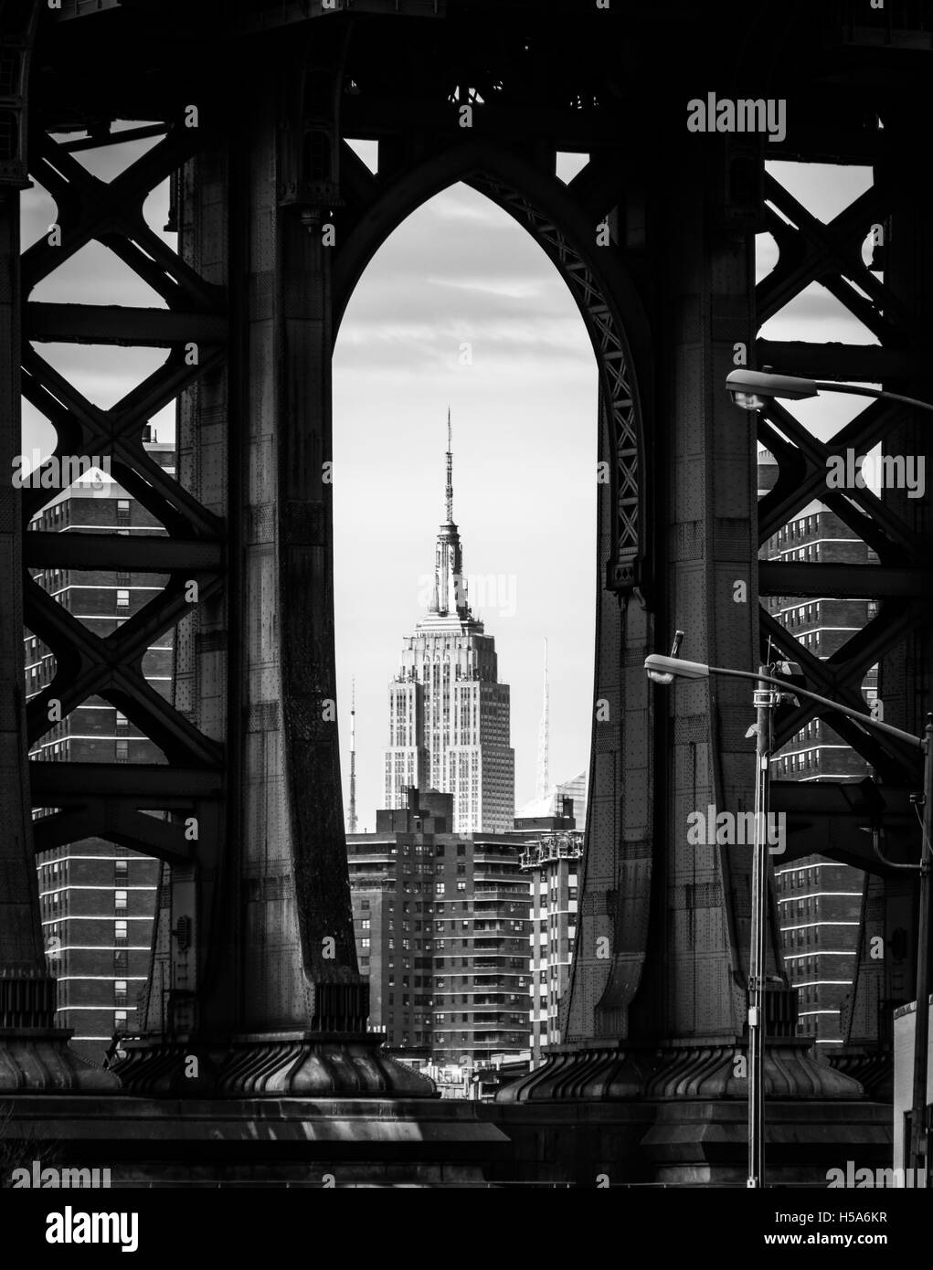 Empire state building encadrée par le pont de Manhattan en noir et blanc Banque D'Images
