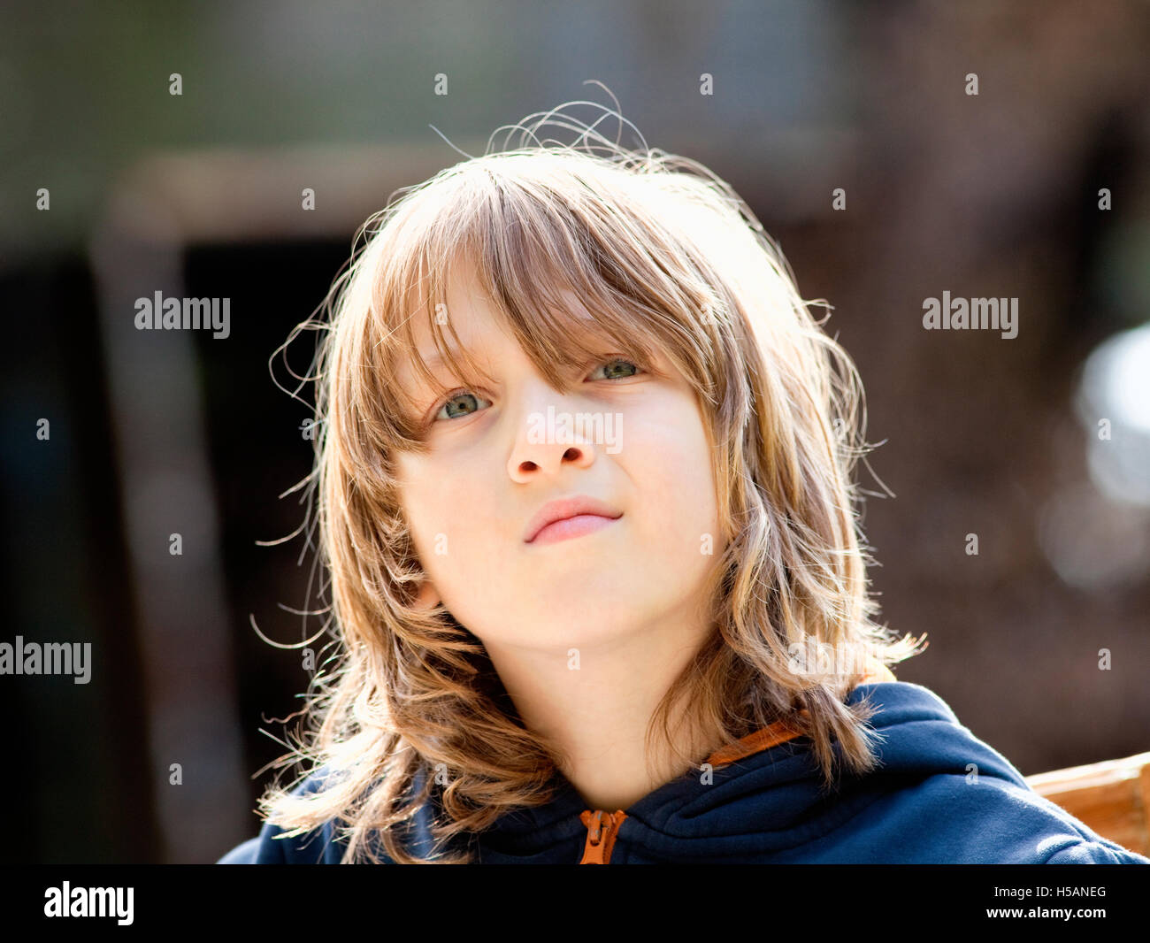 Portrait d'un garçon avec de longs cheveux blonds en plein air Banque D'Images