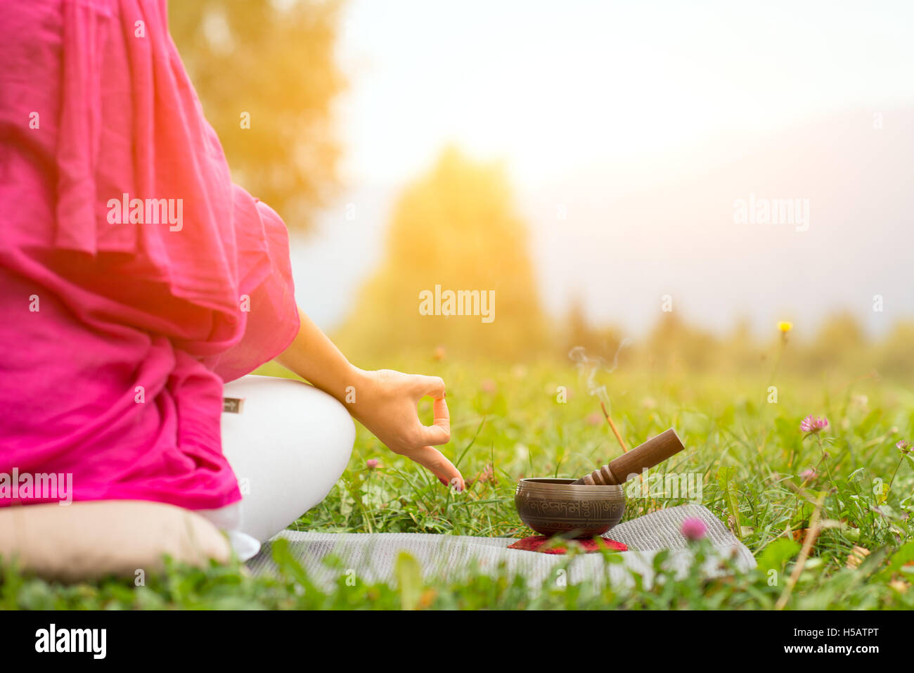 Position de yoga tibétain à côté de Bell dans un pré le soleil Banque D'Images