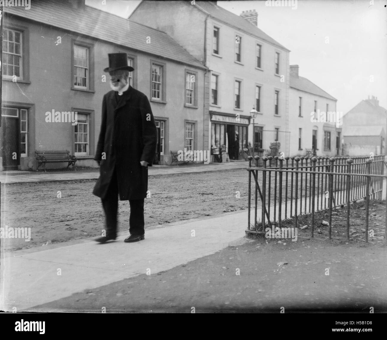 Cette image montre un homme avec une barbe et un chapeau haut de gamme marchant le long d'une route, probablement à Bundoran, une ville côtière en Irlande. La photographie capture un moment de la fin du XIXe ou du début du XXe siècle, représentant le style et la mode de l'époque. Banque D'Images
