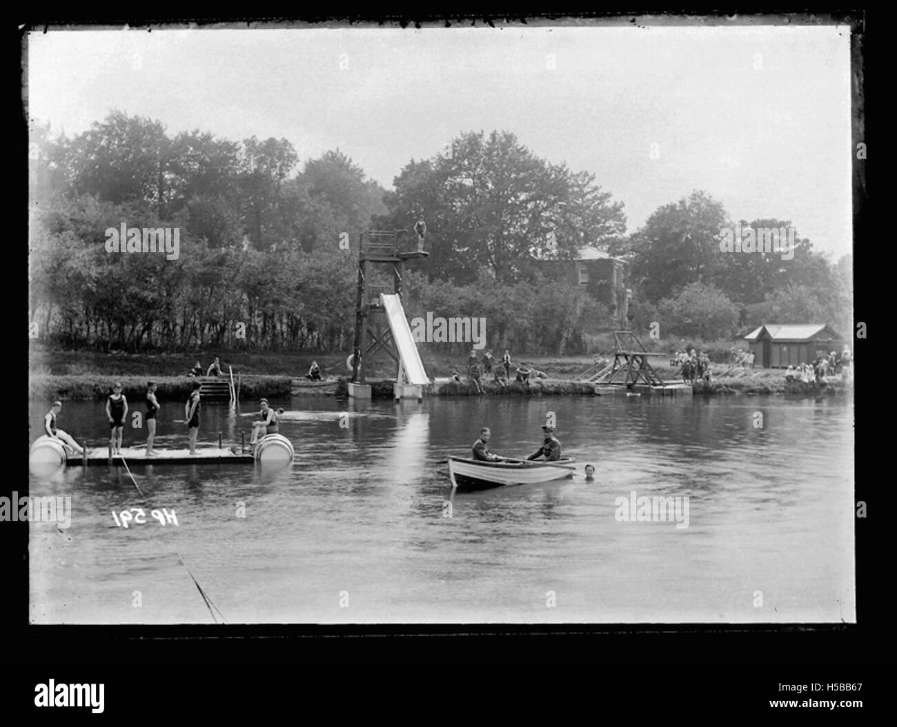 Une scène au bord d'un lac de navigation montre des gens qui apprécient l'eau, avec des baigneurs et des bateaux visibles. Cette image capture une activité récréative dans un lac, probablement du début du XXe siècle, offrant un instantané des loisirs de plein air à cette époque. Banque D'Images
